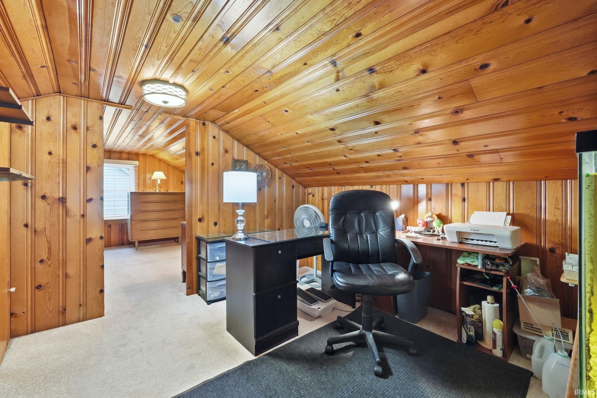 Pine wood paneling on walls and ceiling, wall-mounted ceiling light fixture, and light-toned carpet flooring