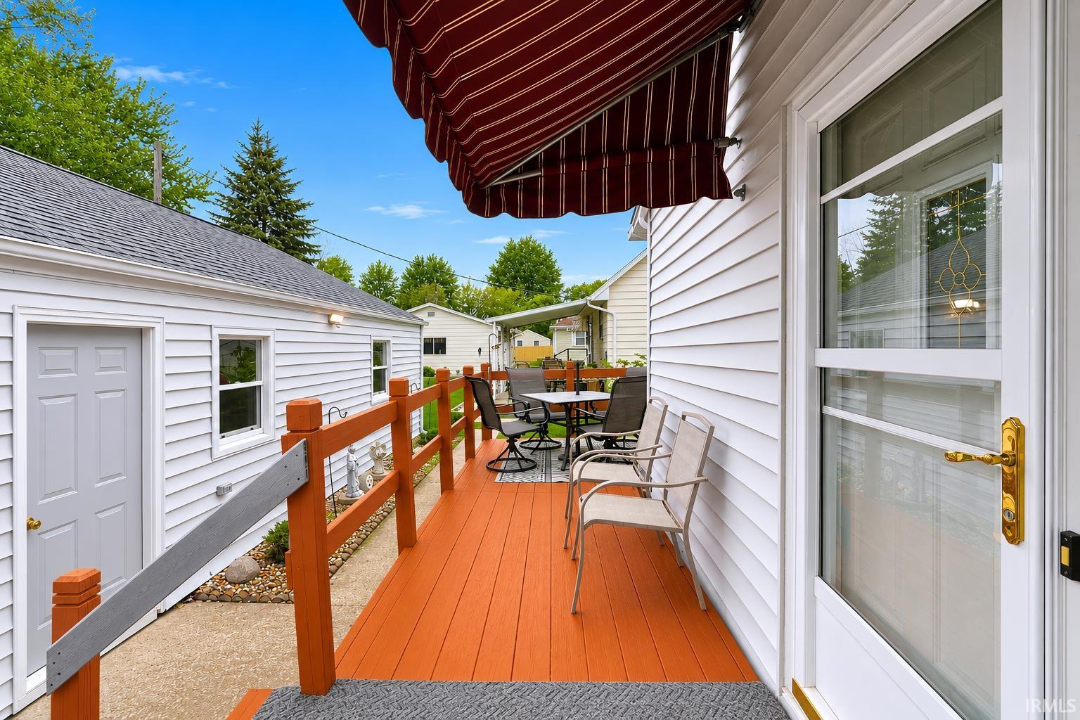 Spacious outdoor deck with a vibrant orange finish, featuring a red and white striped retractable awning