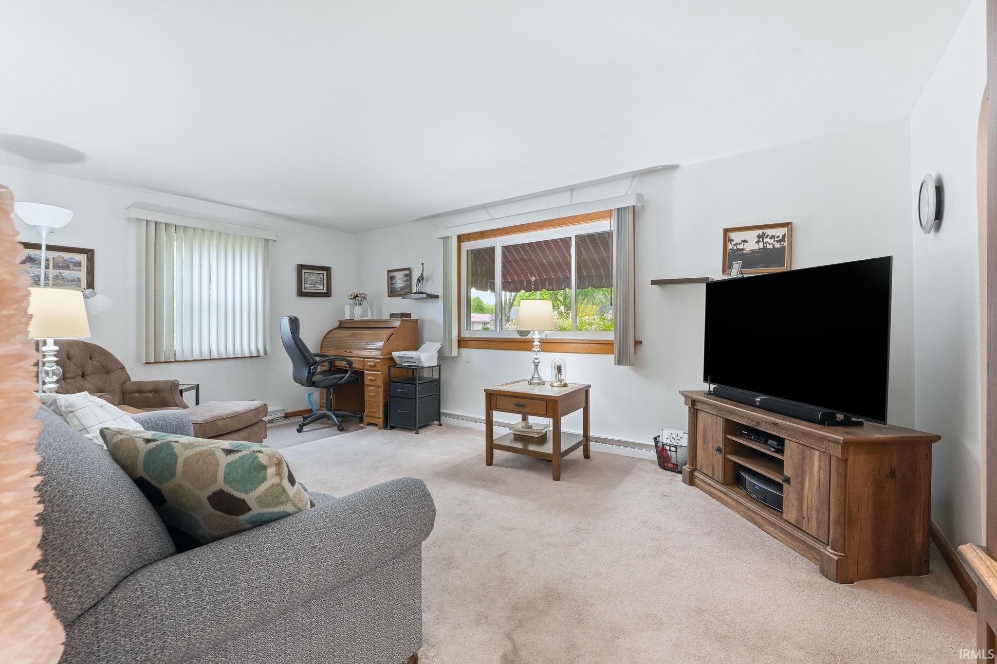 Carpeted living area featuring white walls and multiple windows with blinds