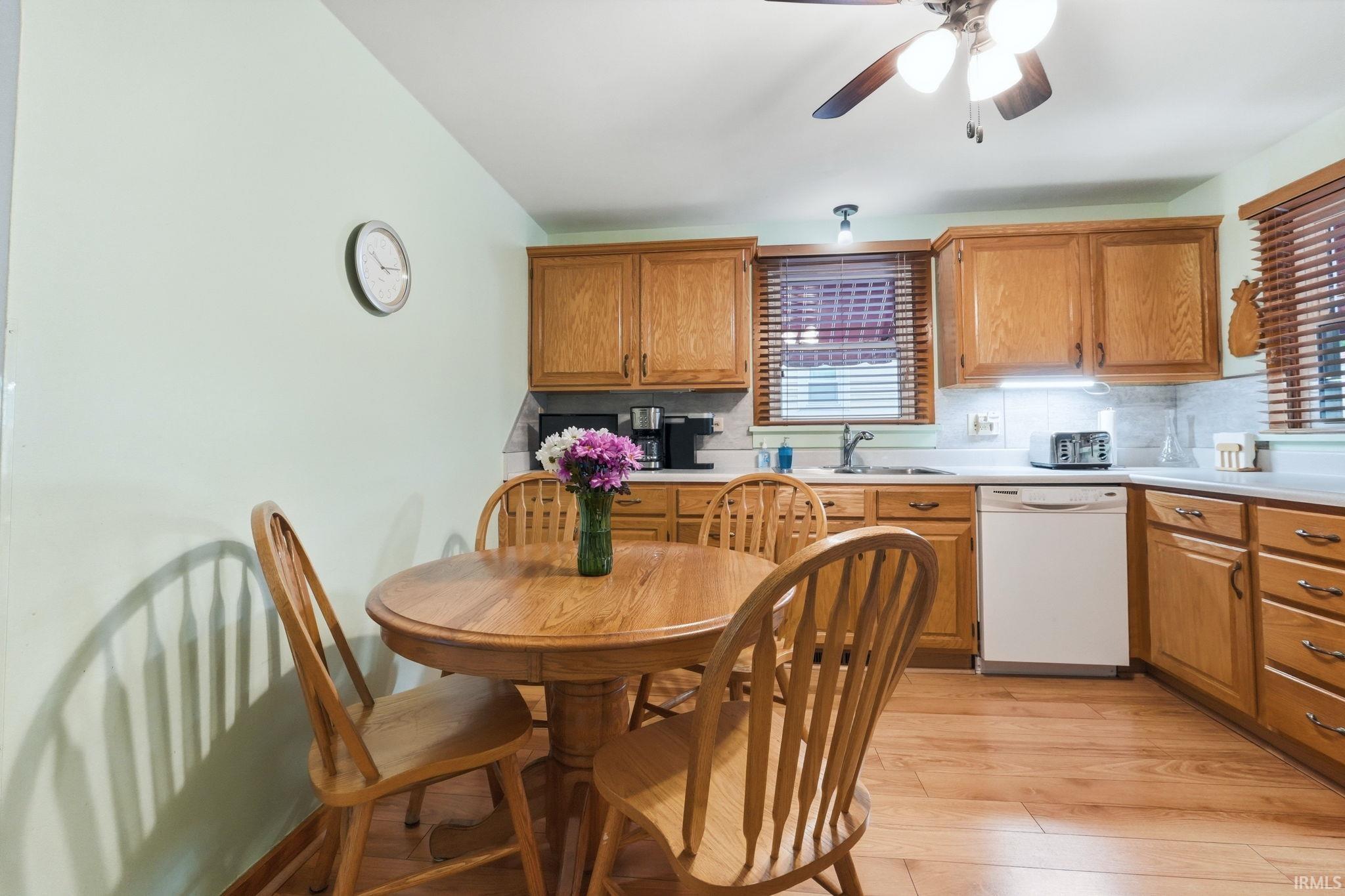 Kitchen featuring wood-finish flooring, wood cabinetry, a ceiling fan, and a light-colored countertop with a tile backsplash