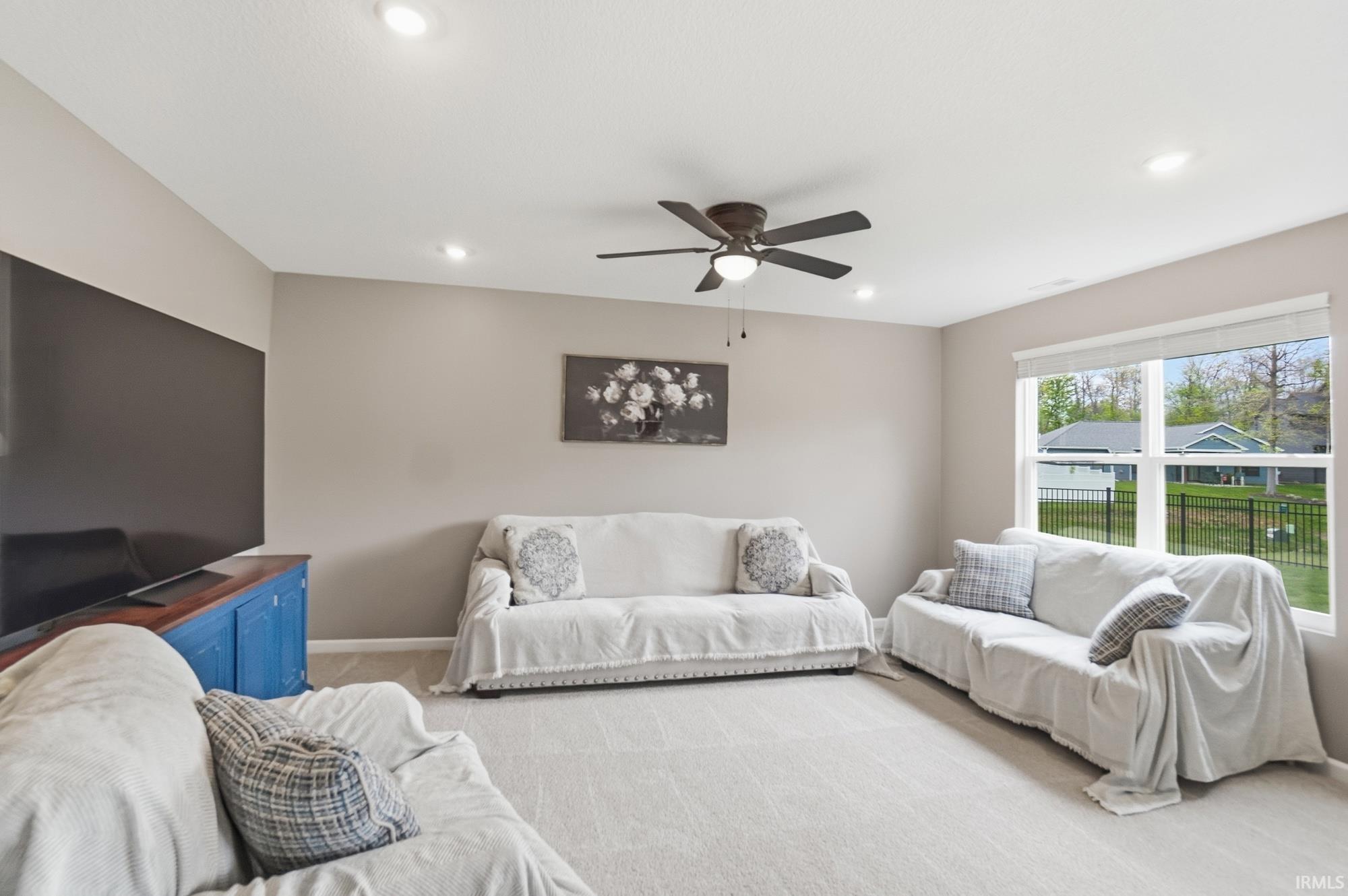 Carpeted living area featuring recessed lighting, a ceiling fan, and a large window with white blinds