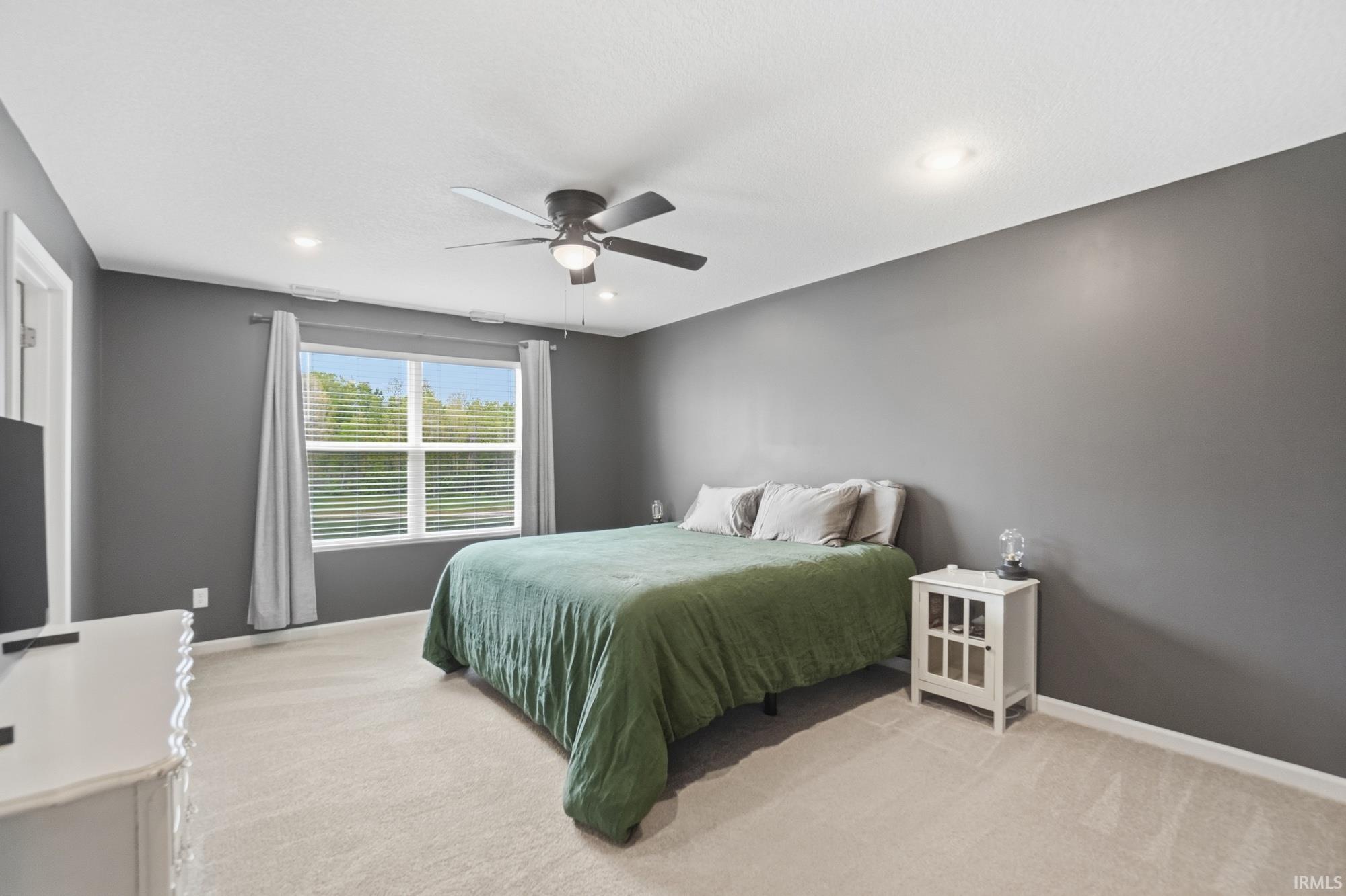 Carpeted bedroom featuring a large window with horizontal blinds, recessed lighting, and a ceiling fan