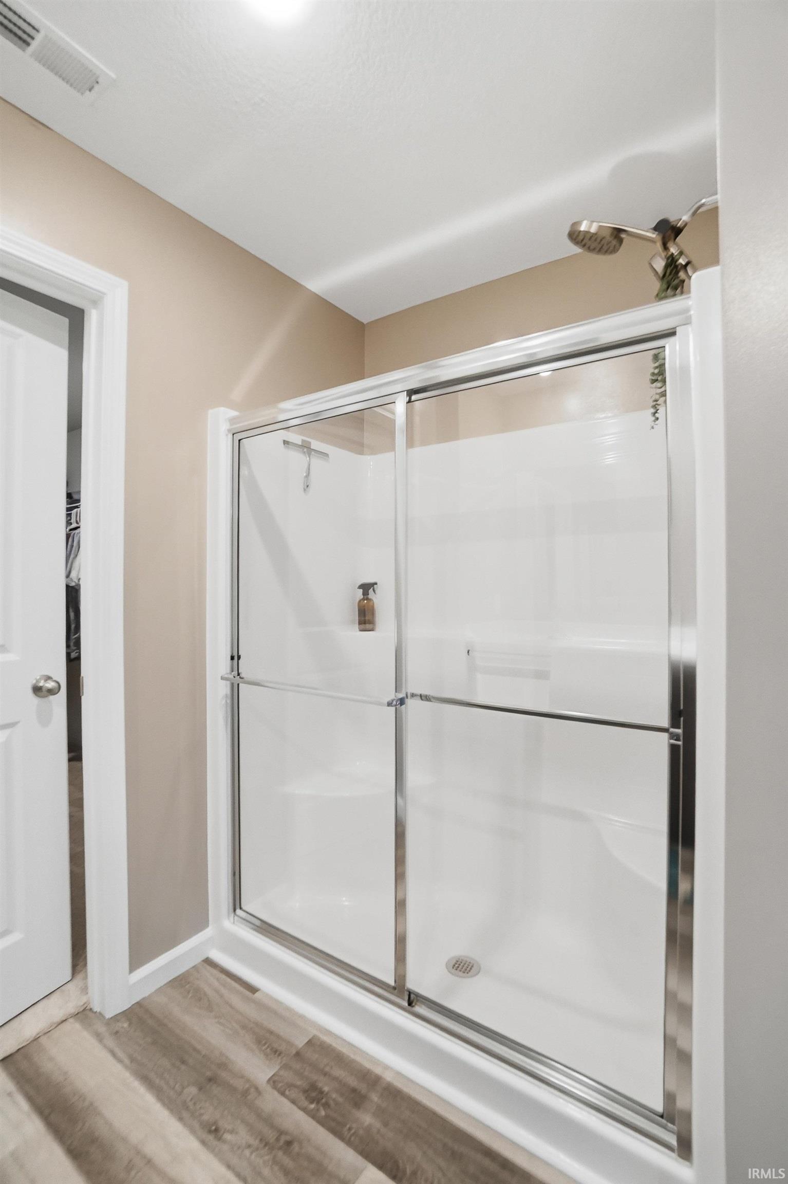 Enclosed shower with sliding glass doors and a white shower base