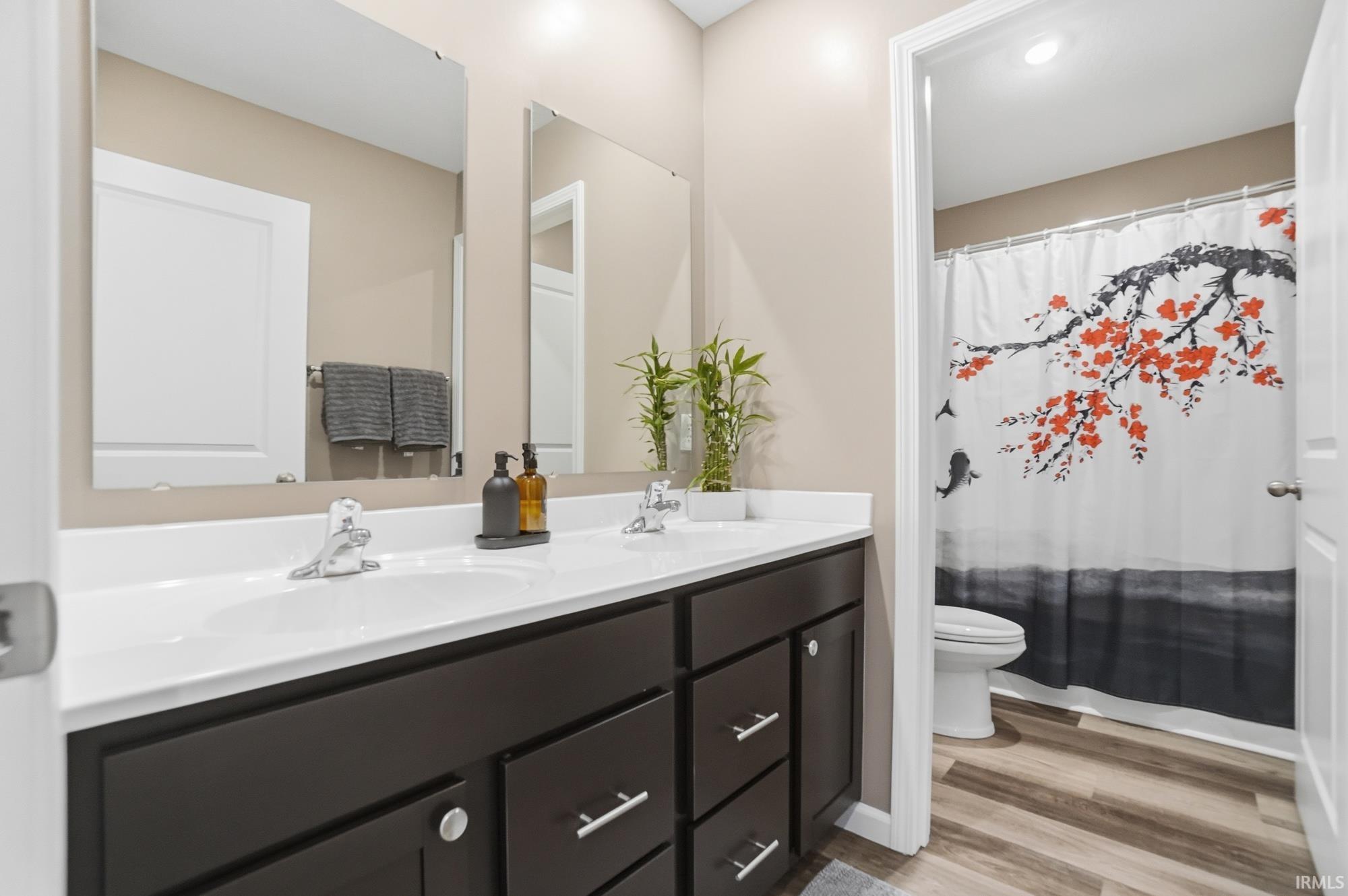 Bathroom featuring a dual vanity with white countertops, chrome faucets, and dark wood-finish cabinetry