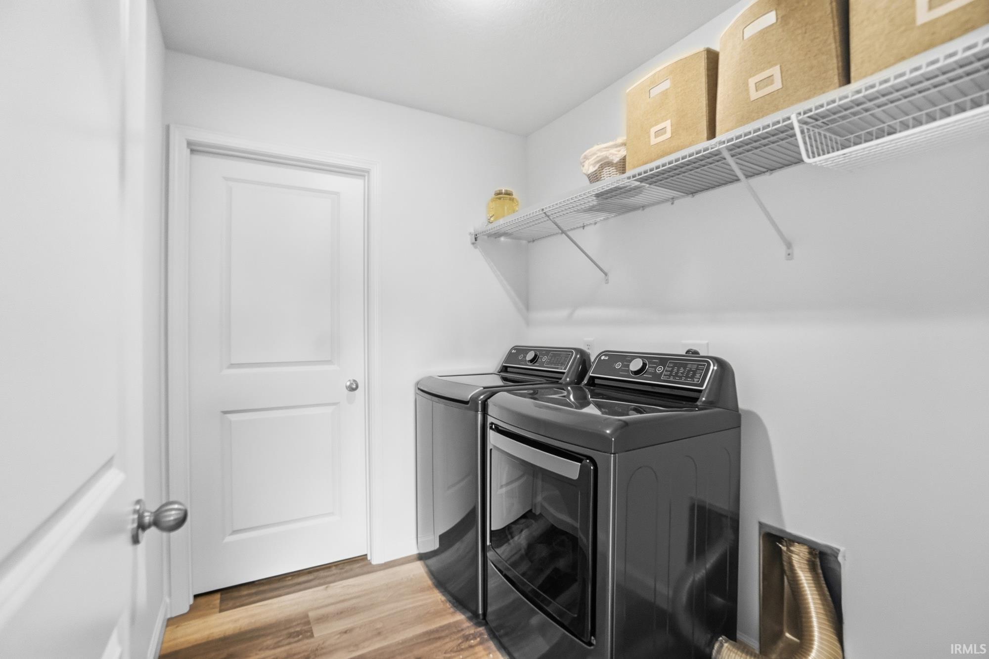 Dedicated laundry space featuring wood-finish flooring, white walls, and a white interior door