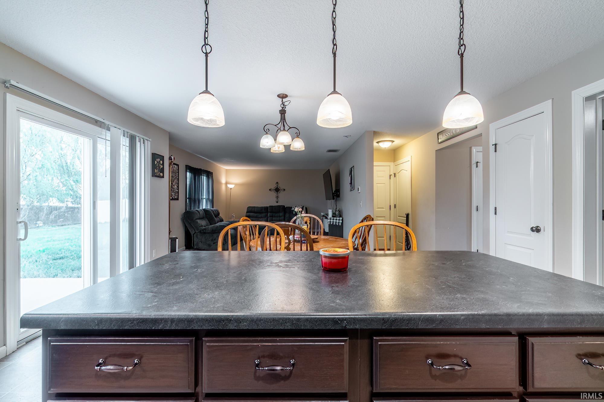 Kitchen island featuring a dark countertop and multiple drawers with bronze hardware