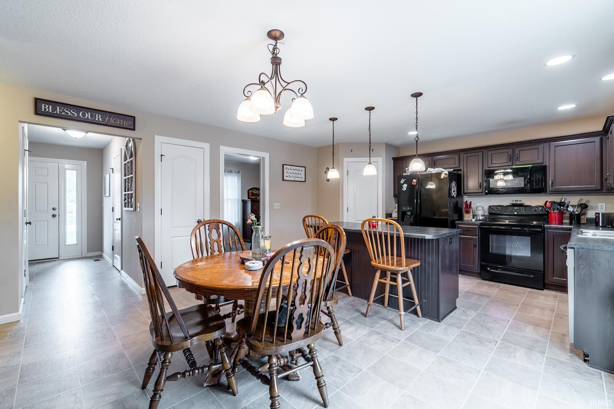 Kitchen featuring dark wood-finish cabinetry, black appliances, and a central island with pendant lighting