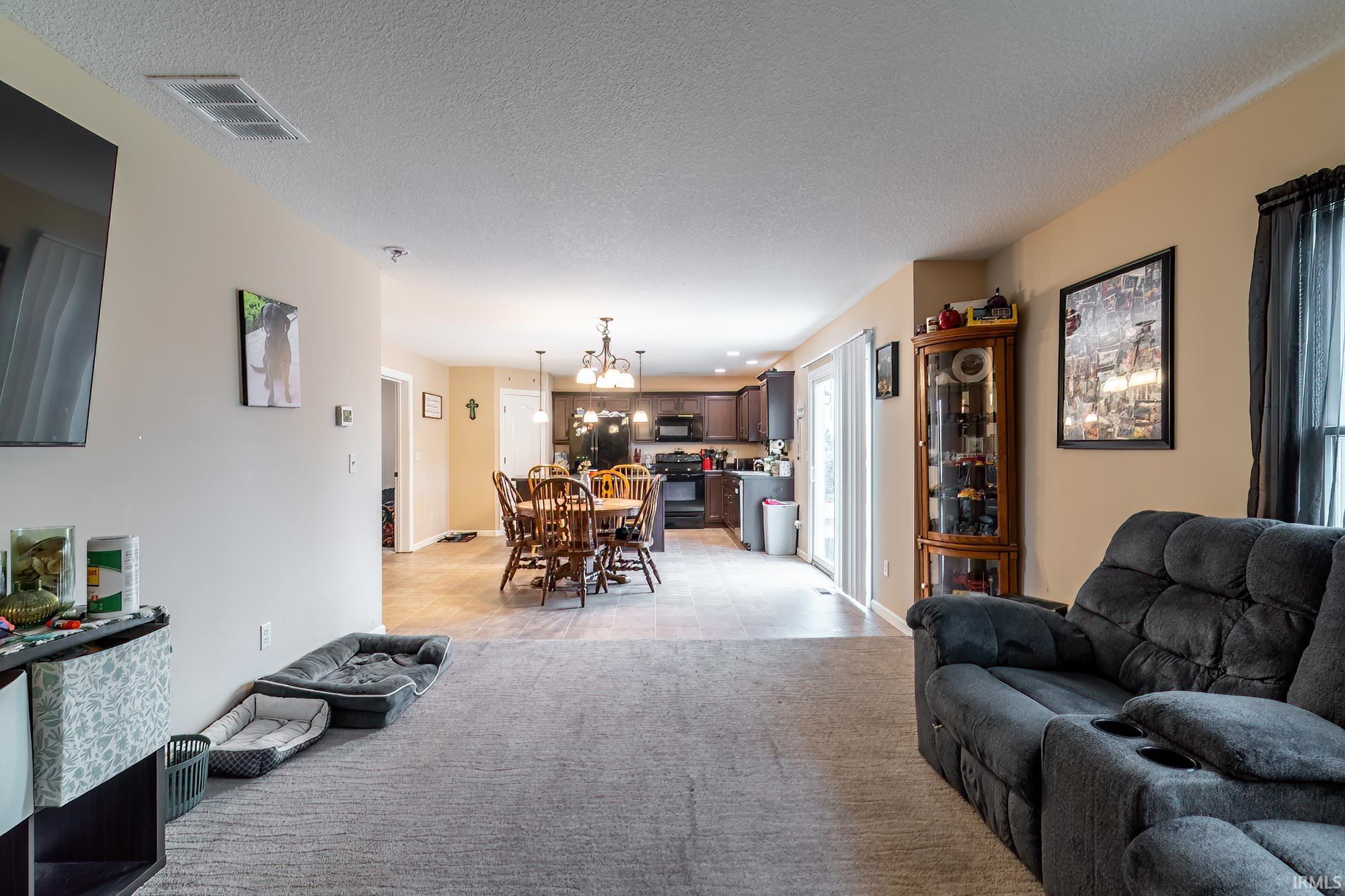 Open-concept living space featuring neutral wall tones and carpeted flooring