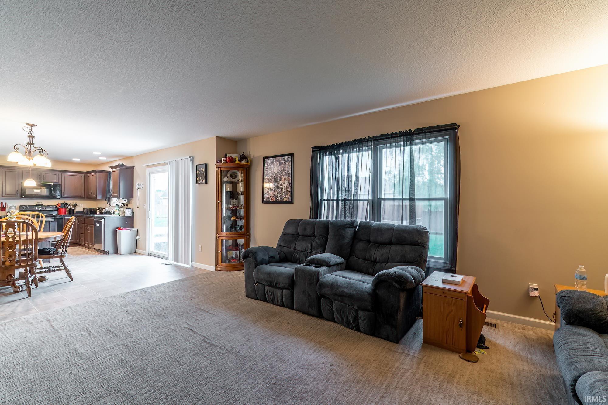 Open-concept living space featuring neutral wall tones and a combination of carpet and wood-finish flooring