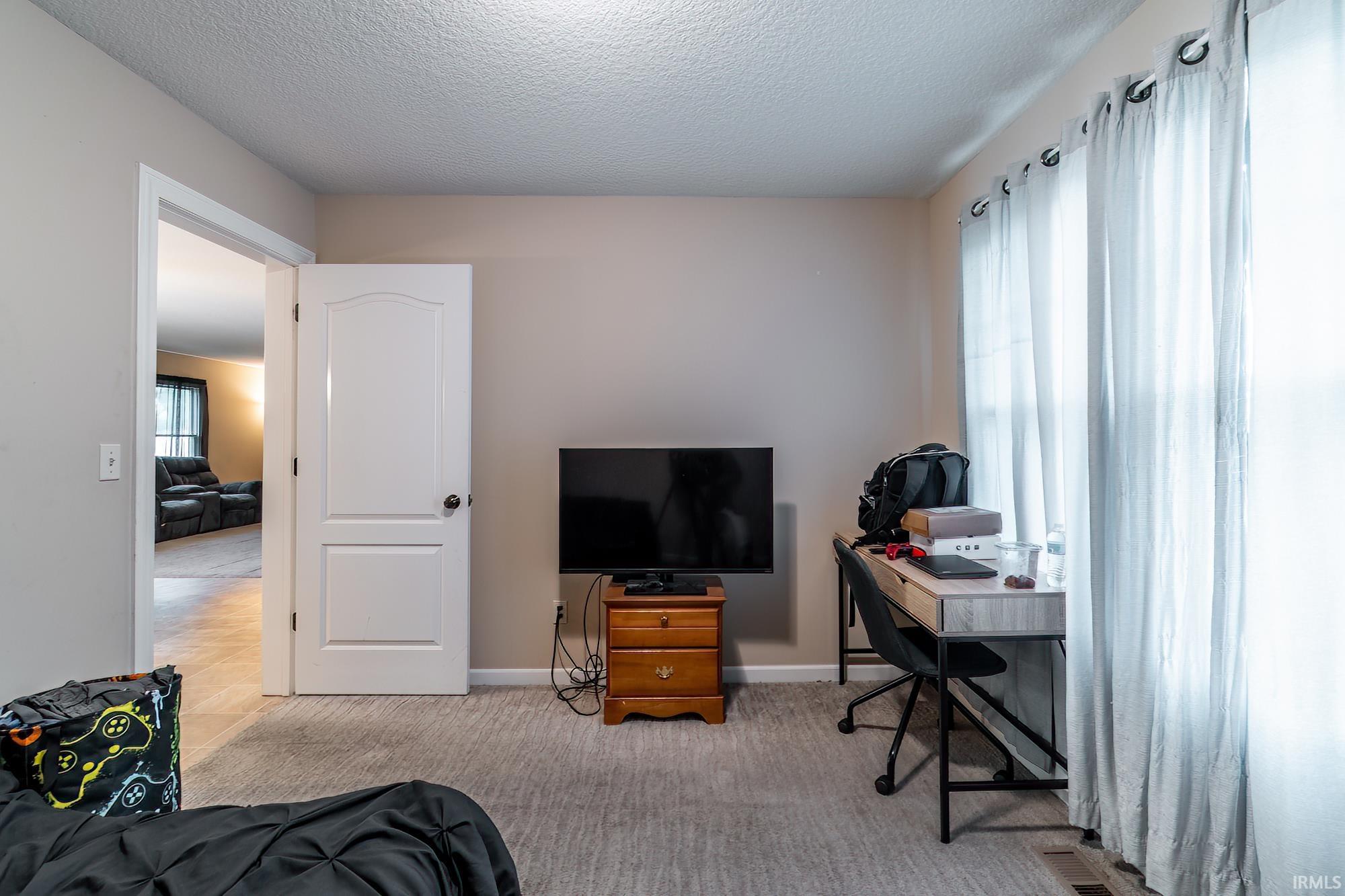 Carpeted room with neutral wall tones and a white interior door with dark hardware