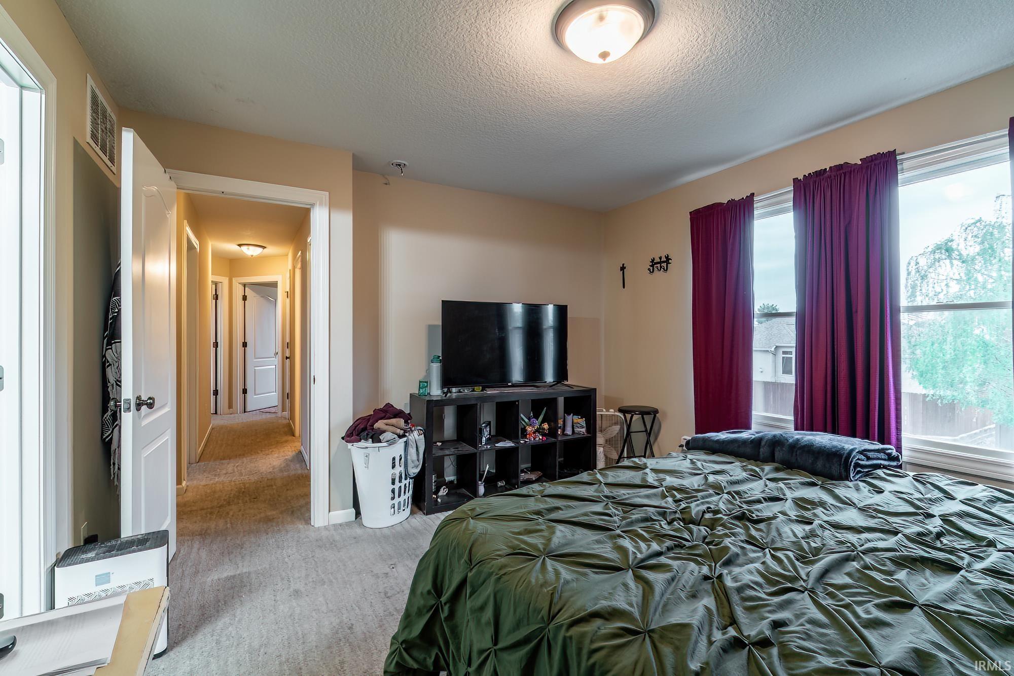 Bedroom featuring two large windows, neutral wall color, and carpeted flooring