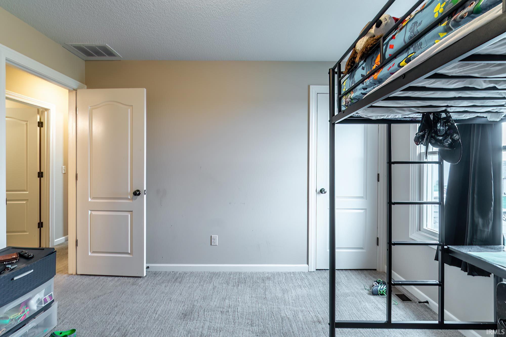 Room featuring light gray wall paint, textured ceiling, light gray carpet flooring, and white baseboards