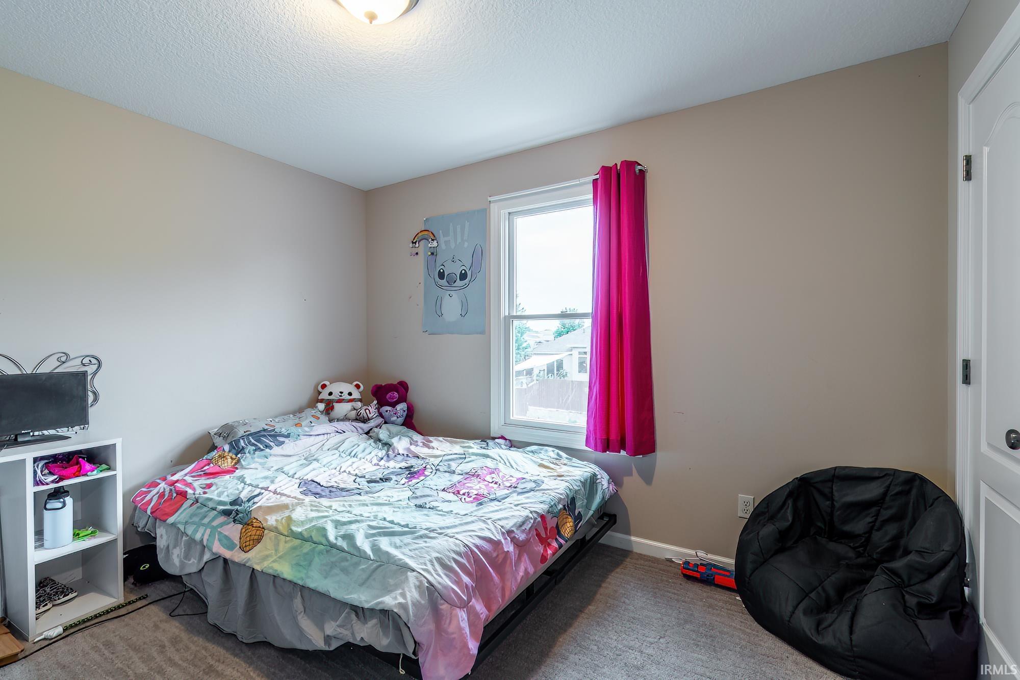 Carpeted room featuring a single window with white trim, a flush-mount ceiling light fixture, and a white interior door with dark hardware