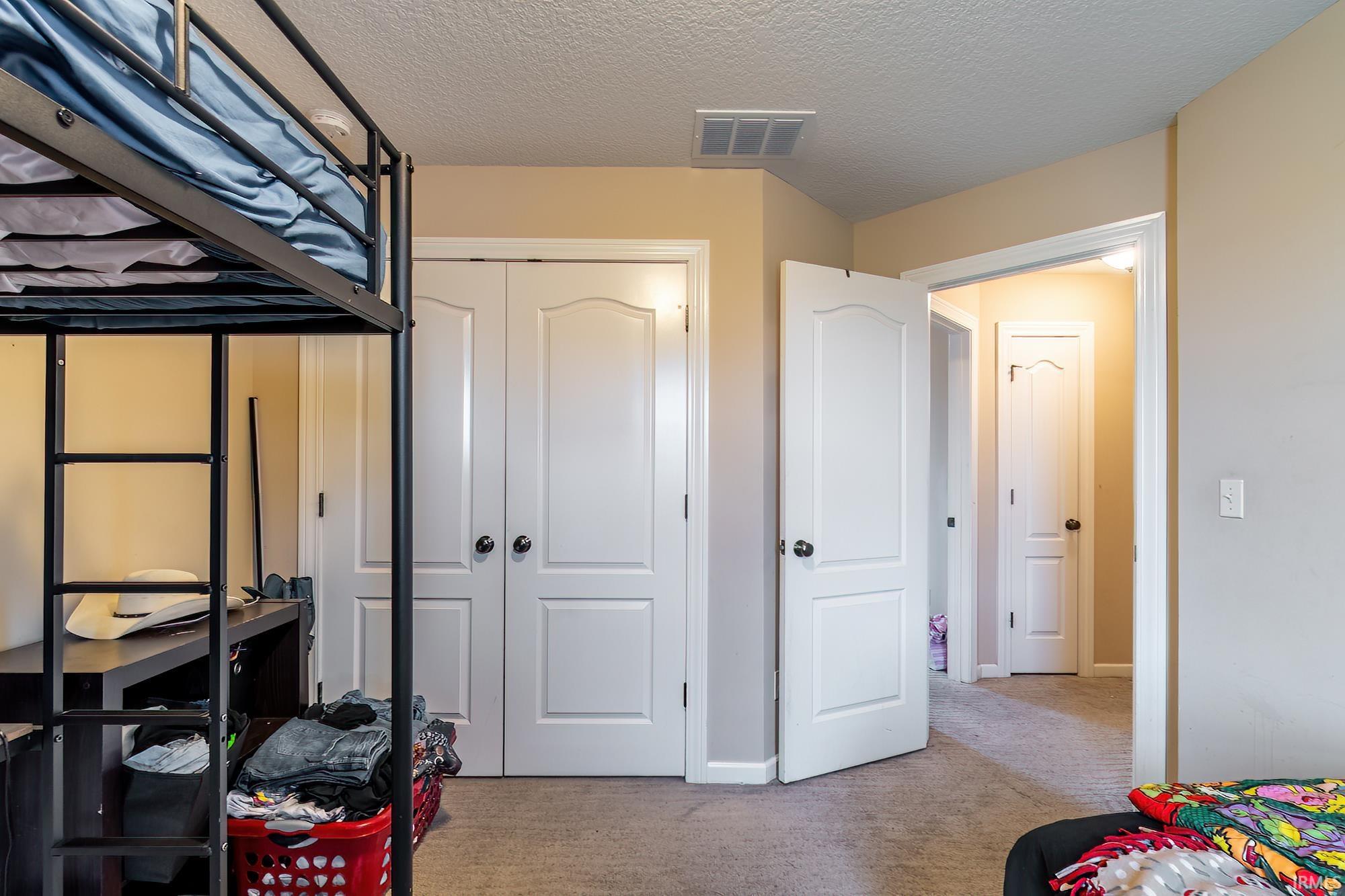 Interior room featuring neutral-toned walls, light-colored carpet flooring, and white two-panel doors with black hardware