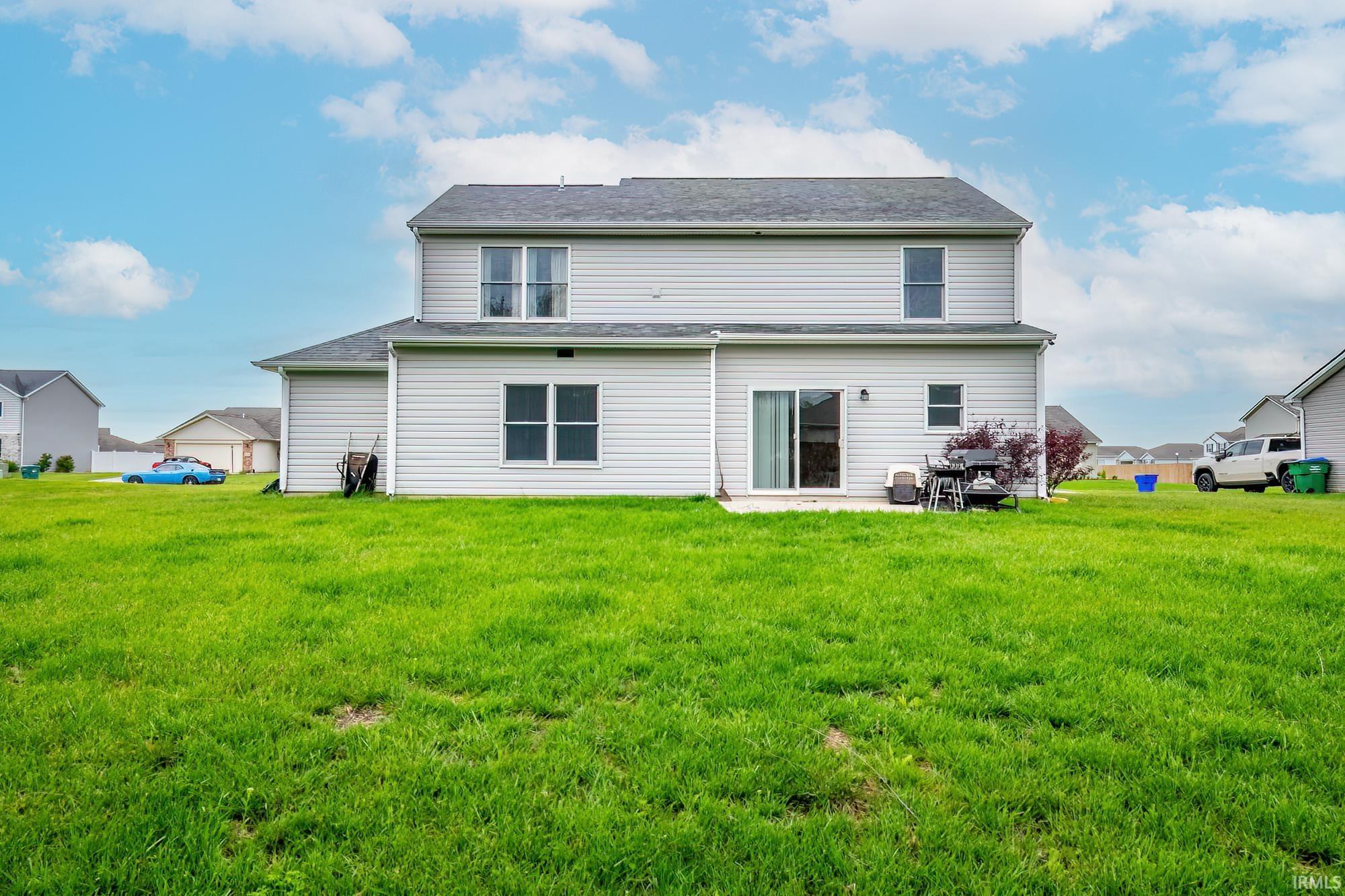 Expansive rear yard featuring a large green lawn and a two-story residence with light-colored siding