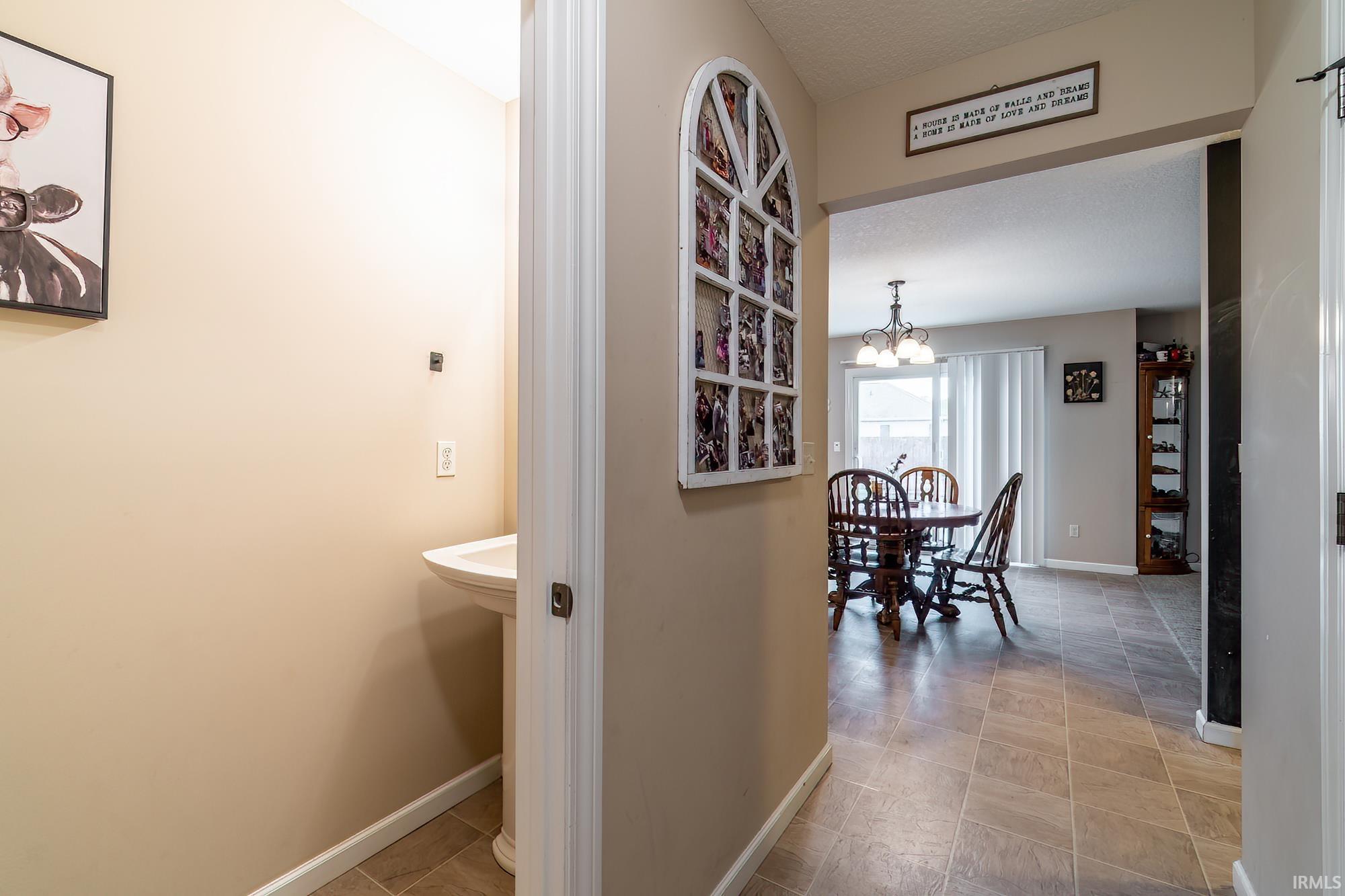 Entryway featuring ceramic tile flooring, a pedestal sink, and an arched doorway opening to a dining area with sliding glass doors