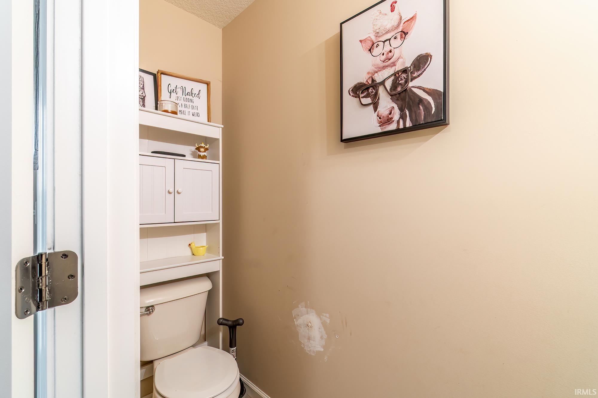White over-toilet storage unit featuring closed cabinetry and open shelving