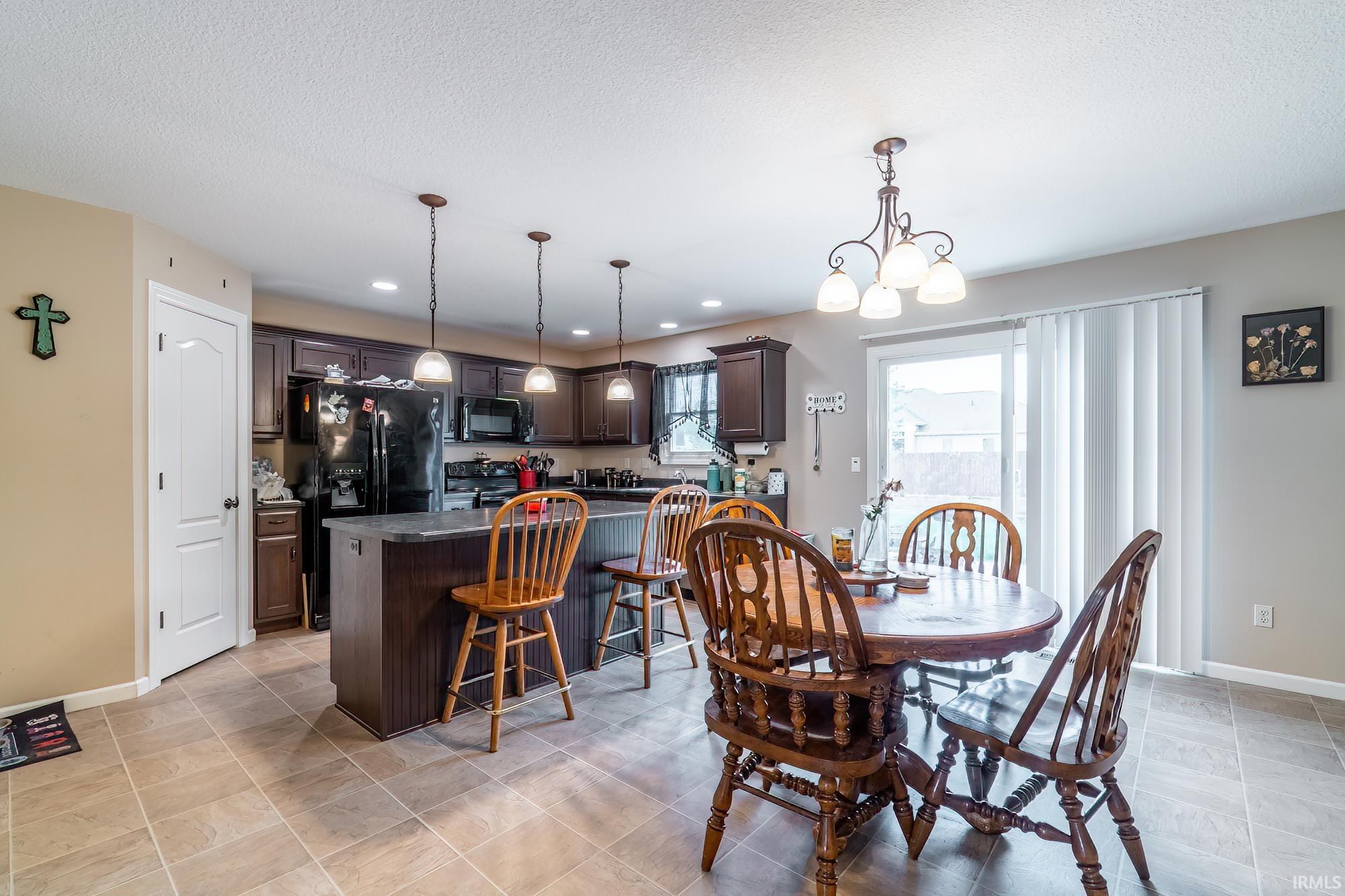 Kitchen and dining area featuring dark wood cabinetry, a central island with bar seating, and tile flooring