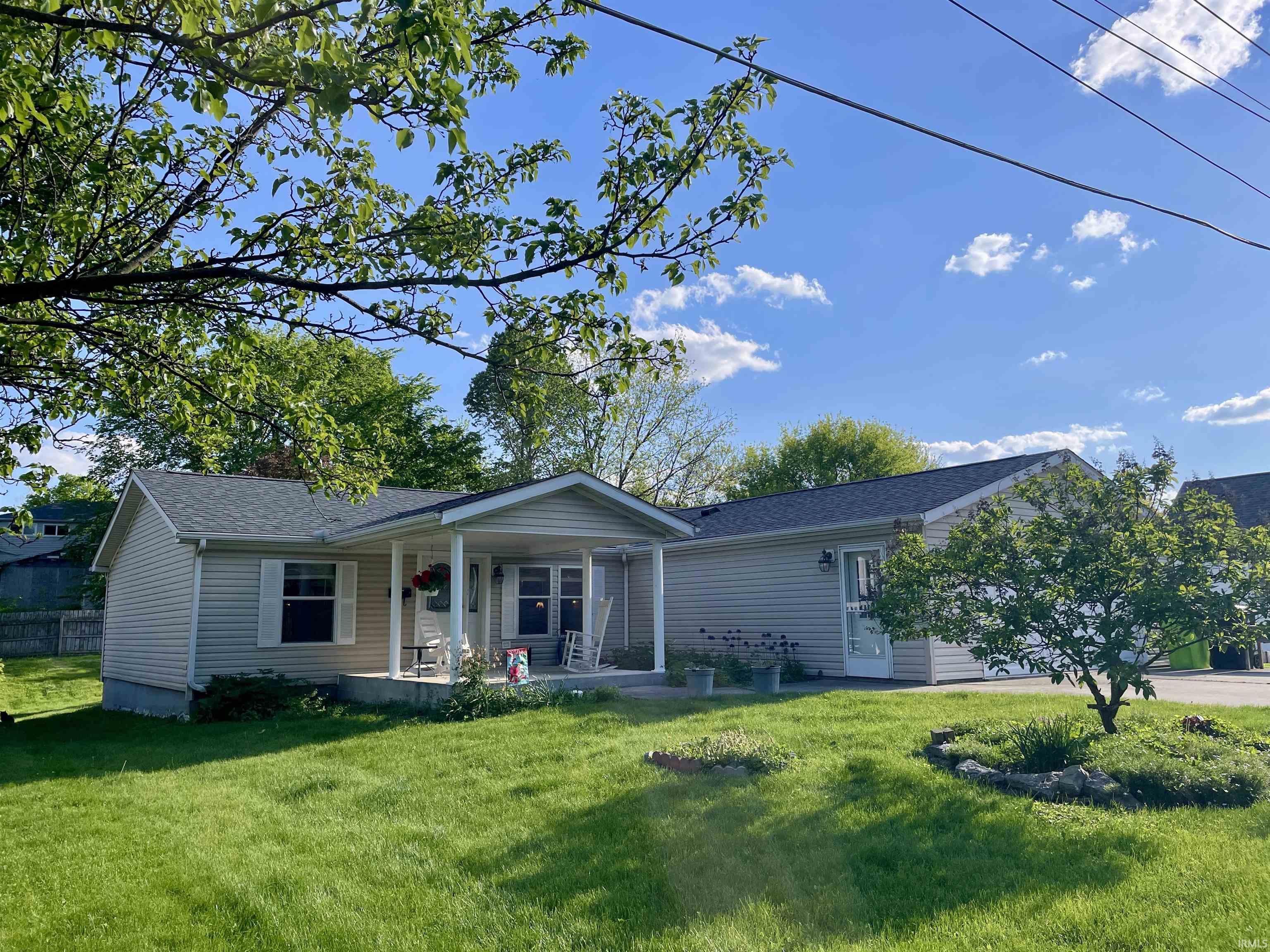 Light-colored siding exterior with a covered front porch, white window shutters, and a dark-shingled roof