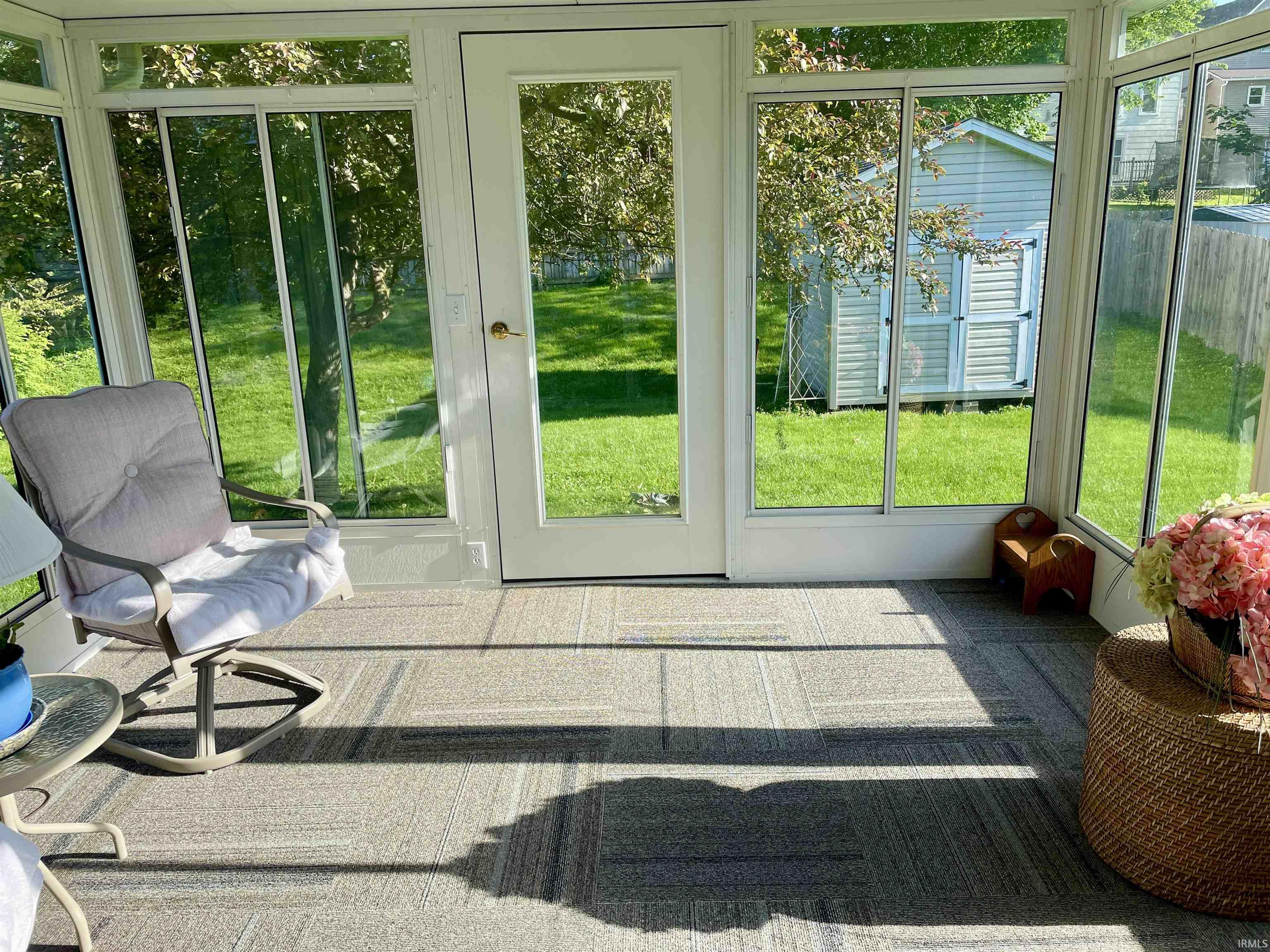 Sunroom featuring a full-light exterior door, multiple window panels, and modular carpet tile flooring