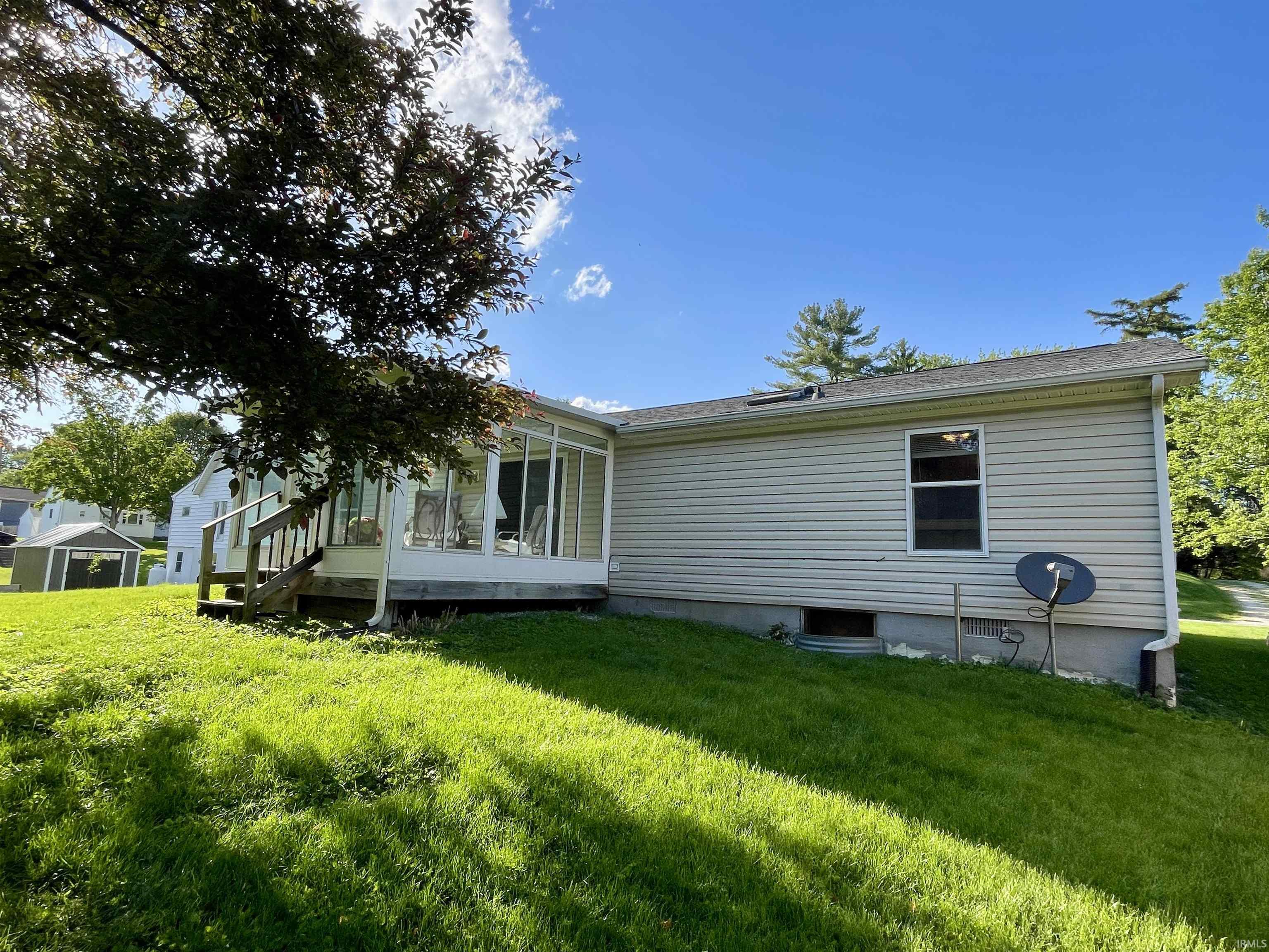 Exterior view featuring tan vinyl siding and a sunroom addition