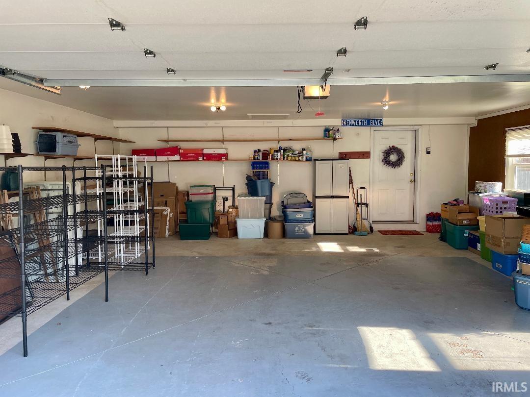 Spacious garage featuring a concrete floor, overhead lighting, and an interior access door