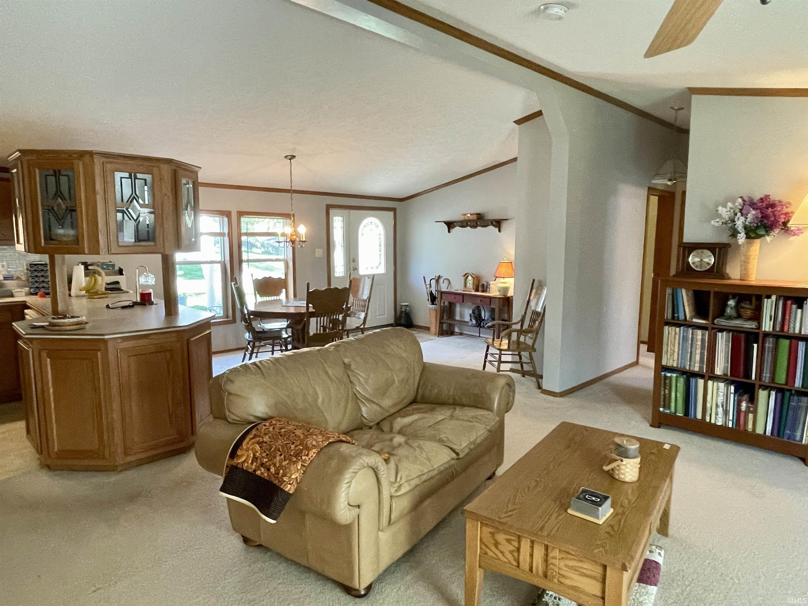 Carpeted living area featuring a built-in wood-finish bookcase, sloped ceilings, and wood-finish trim