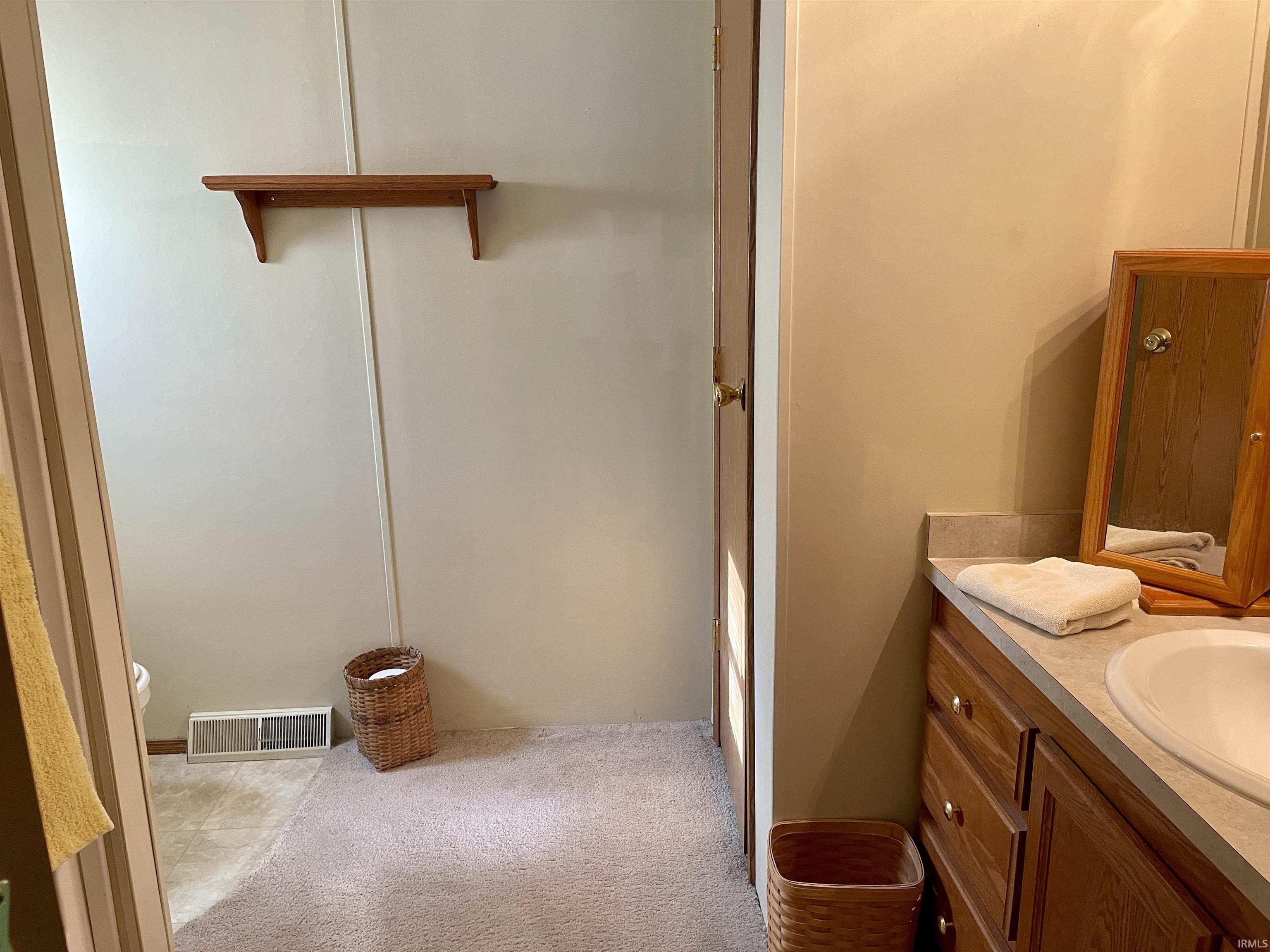 Bathroom vanity featuring wood-finish cabinetry, a built-in sink, and a light-toned countertop