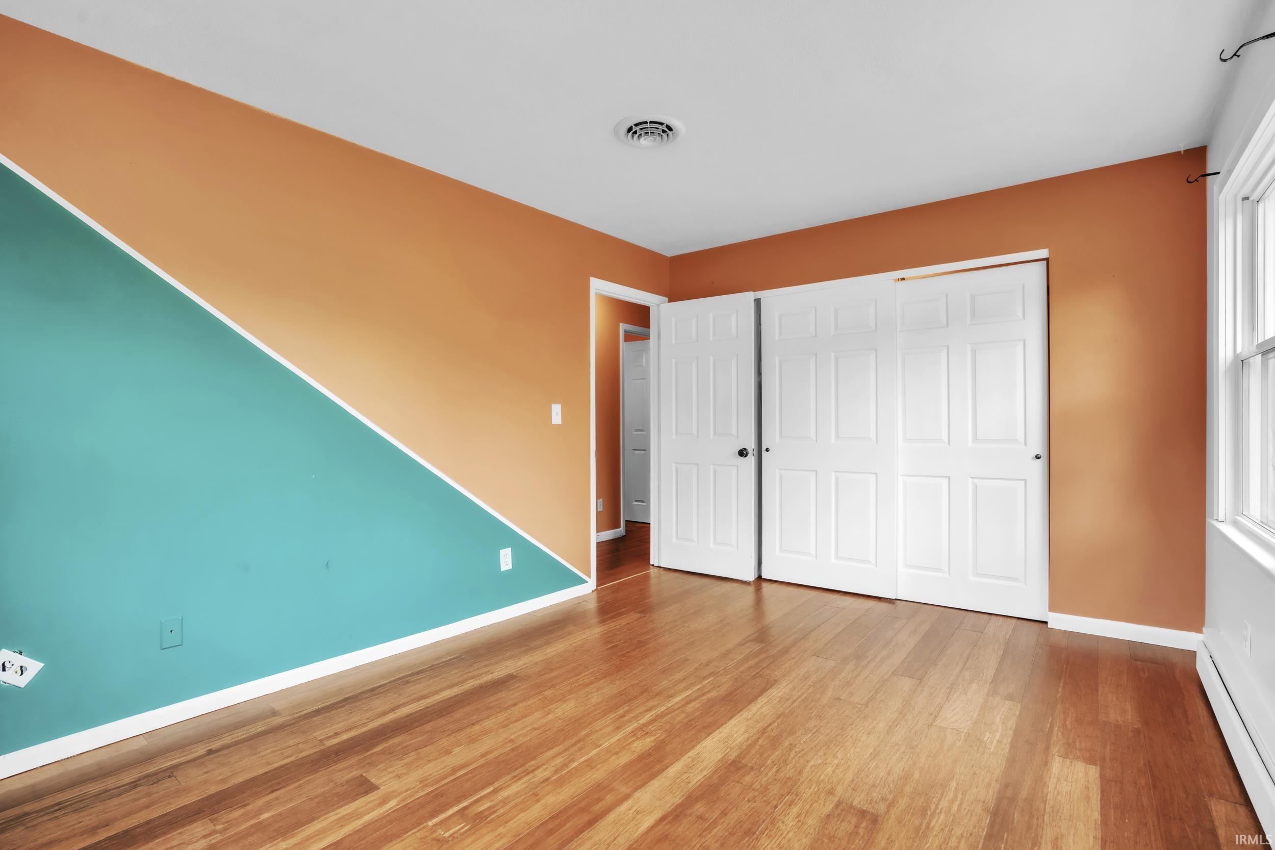 Room featuring wood-finish flooring, white baseboards, and a two-tone wall design