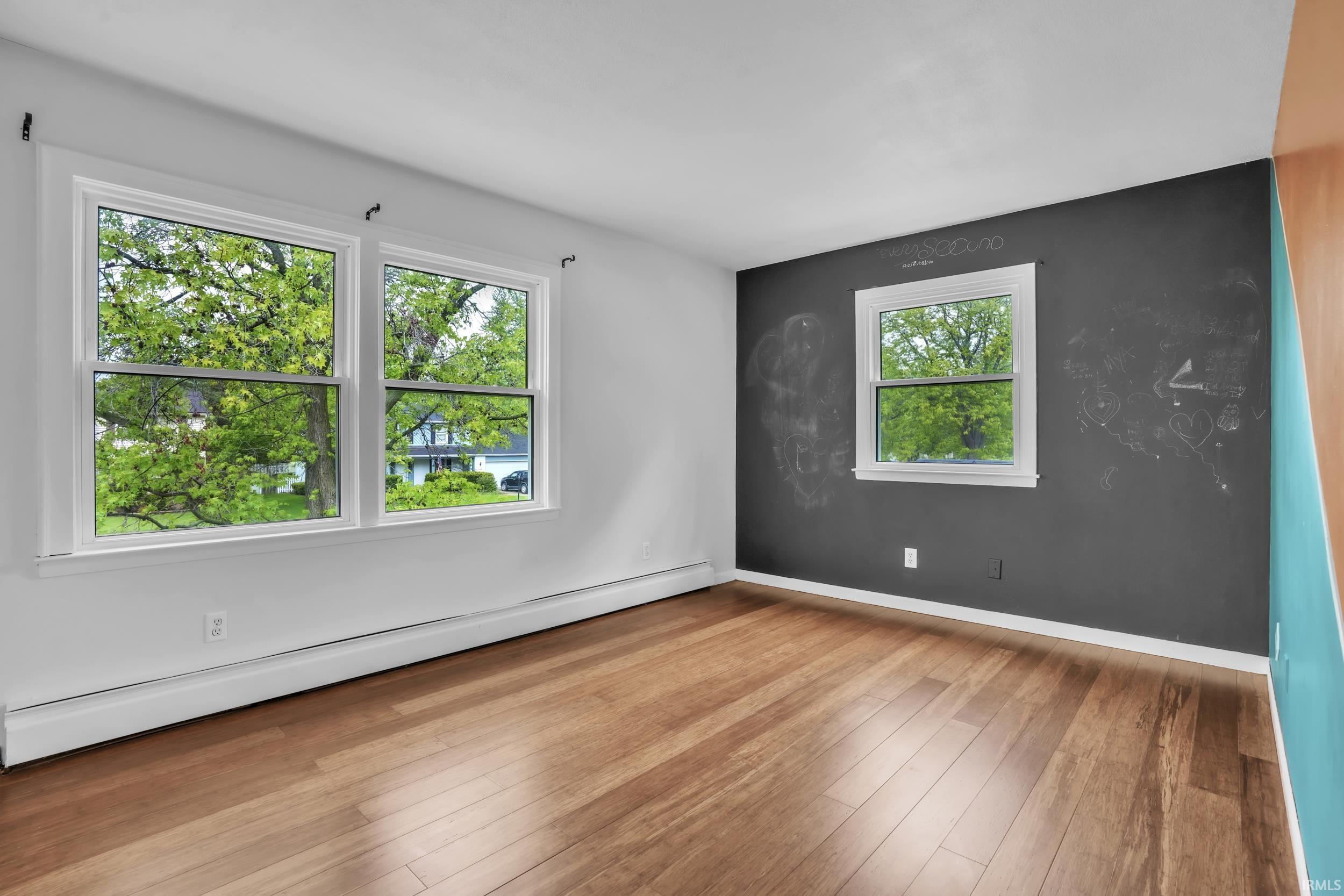 Room featuring wood-finish flooring, white painted walls, and a prominent accent wall