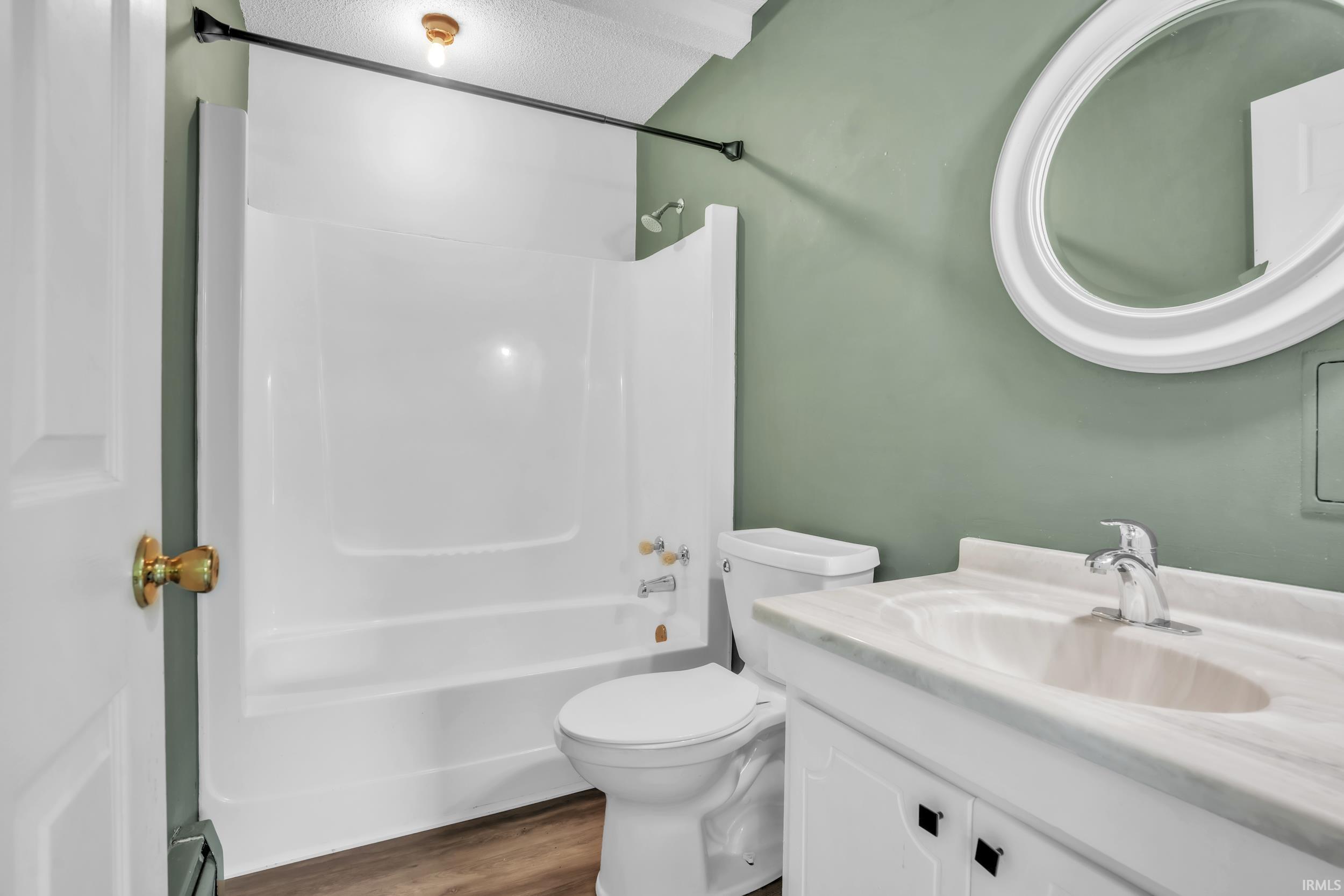 Bathroom featuring a white vanity with a single basin sink, a large oval mirror, and a full shower-tub combination