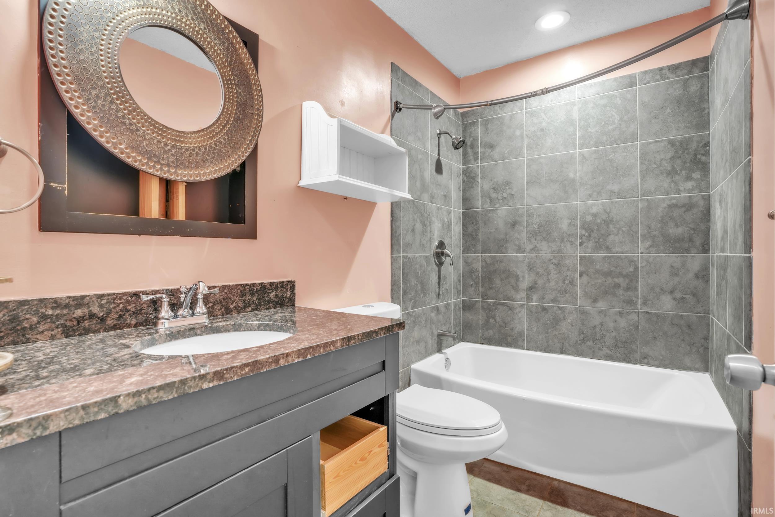 Bathroom featuring a dark wood-finish vanity with a stone countertop and an undermount sink