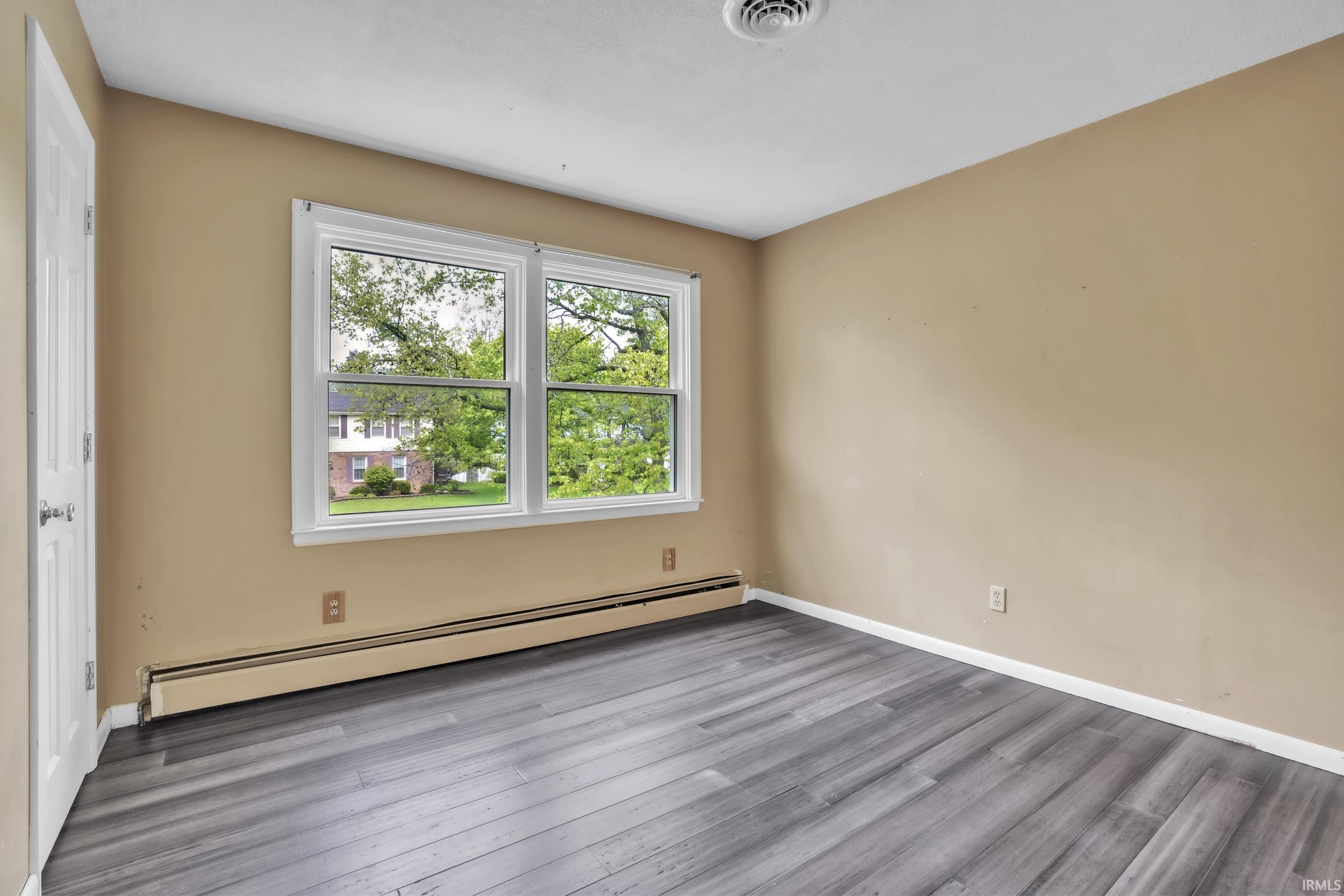 Room featuring wood-finish flooring, neutral wall paint, and white trim