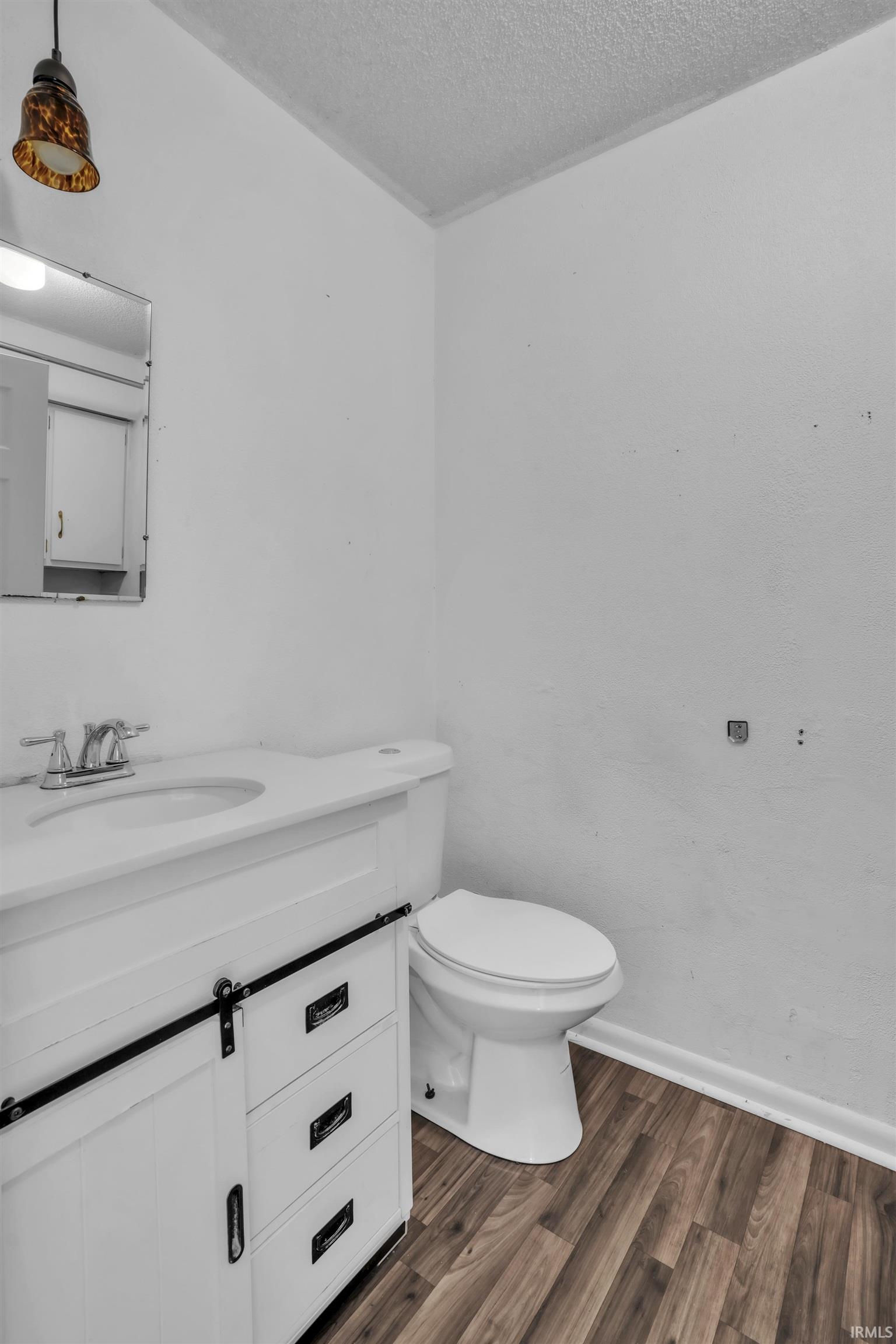 Bathroom featuring a white vanity with integrated sink, chrome faucet, and barn-door style cabinet with drawers