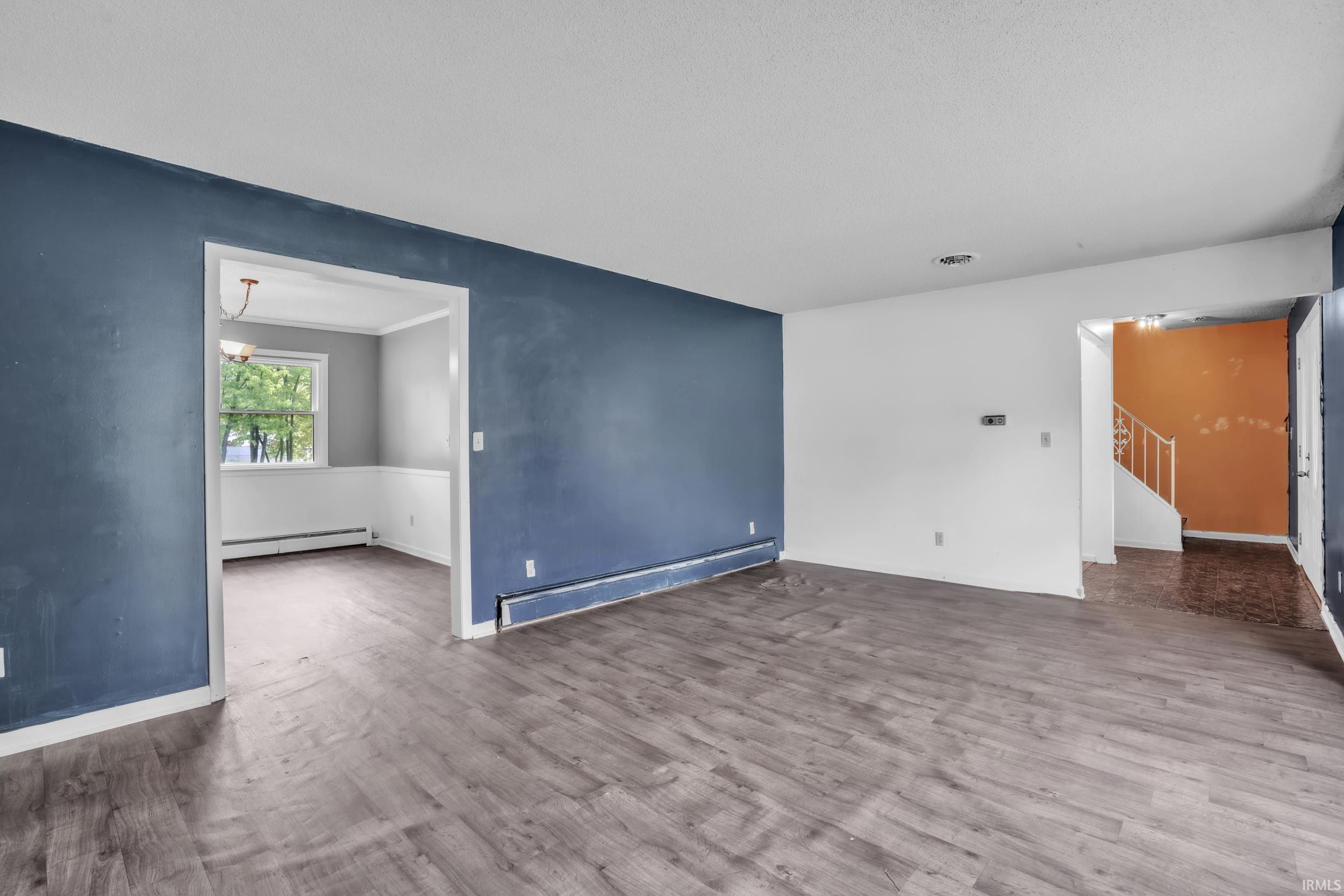 Spacious room featuring wood-finish flooring and a wide doorway opening to an additional area