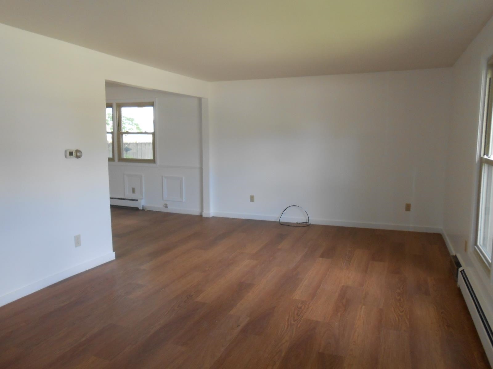 Expansive interior space featuring wood-finish flooring, white walls, and bright windows