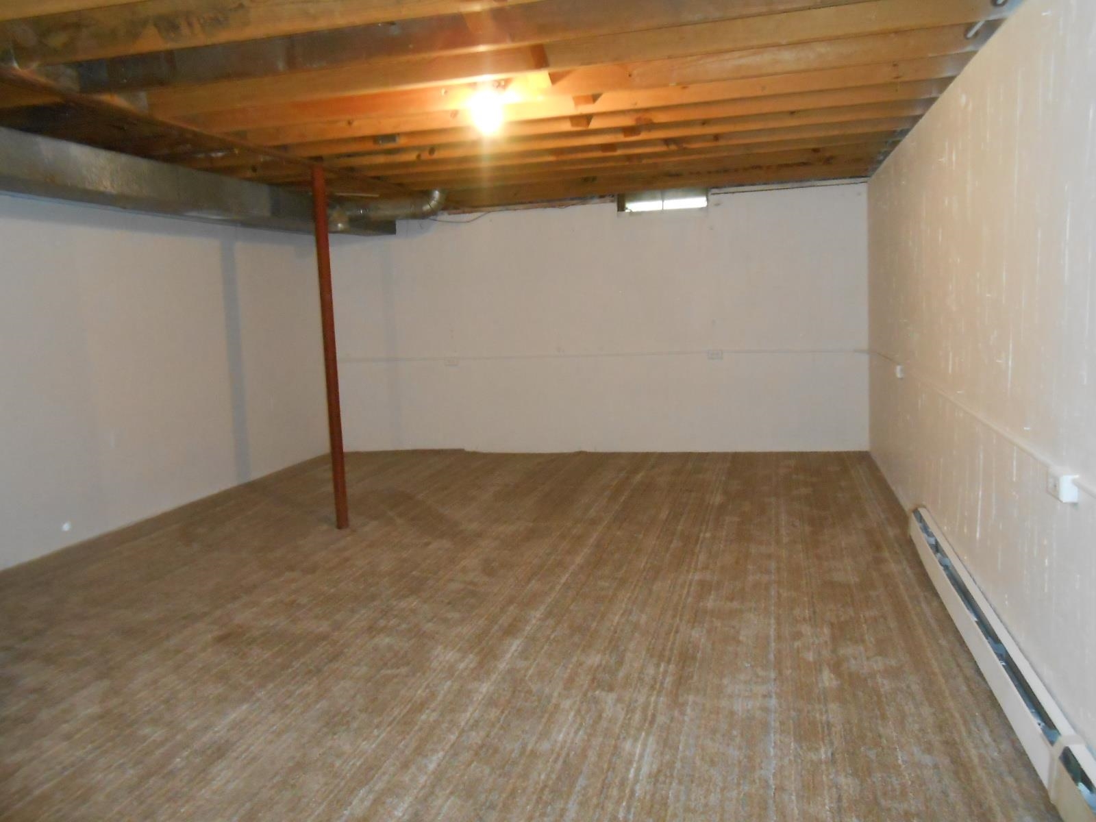Expansive lower level featuring exposed wood joists, a support column, finished walls, and baseboard heating