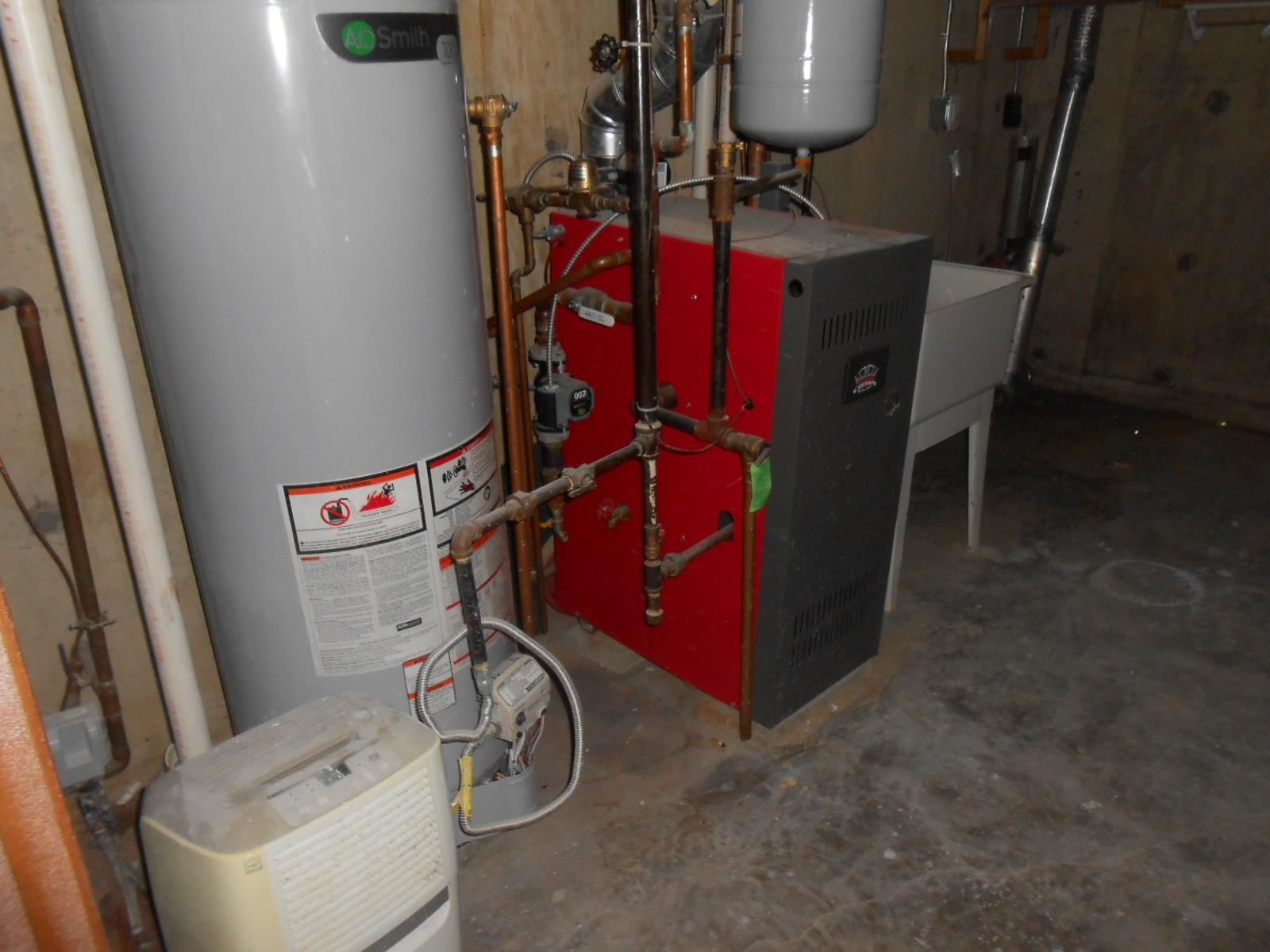 Utility area featuring a water heater, boiler system with copper piping, and a utility sink