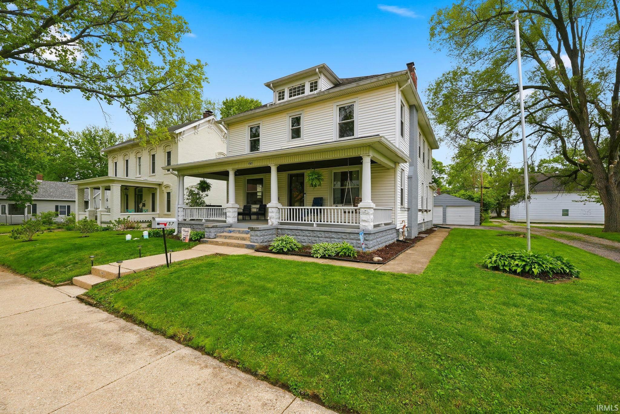 Two-story residence featuring white siding and a covered front porch with white railings and columns