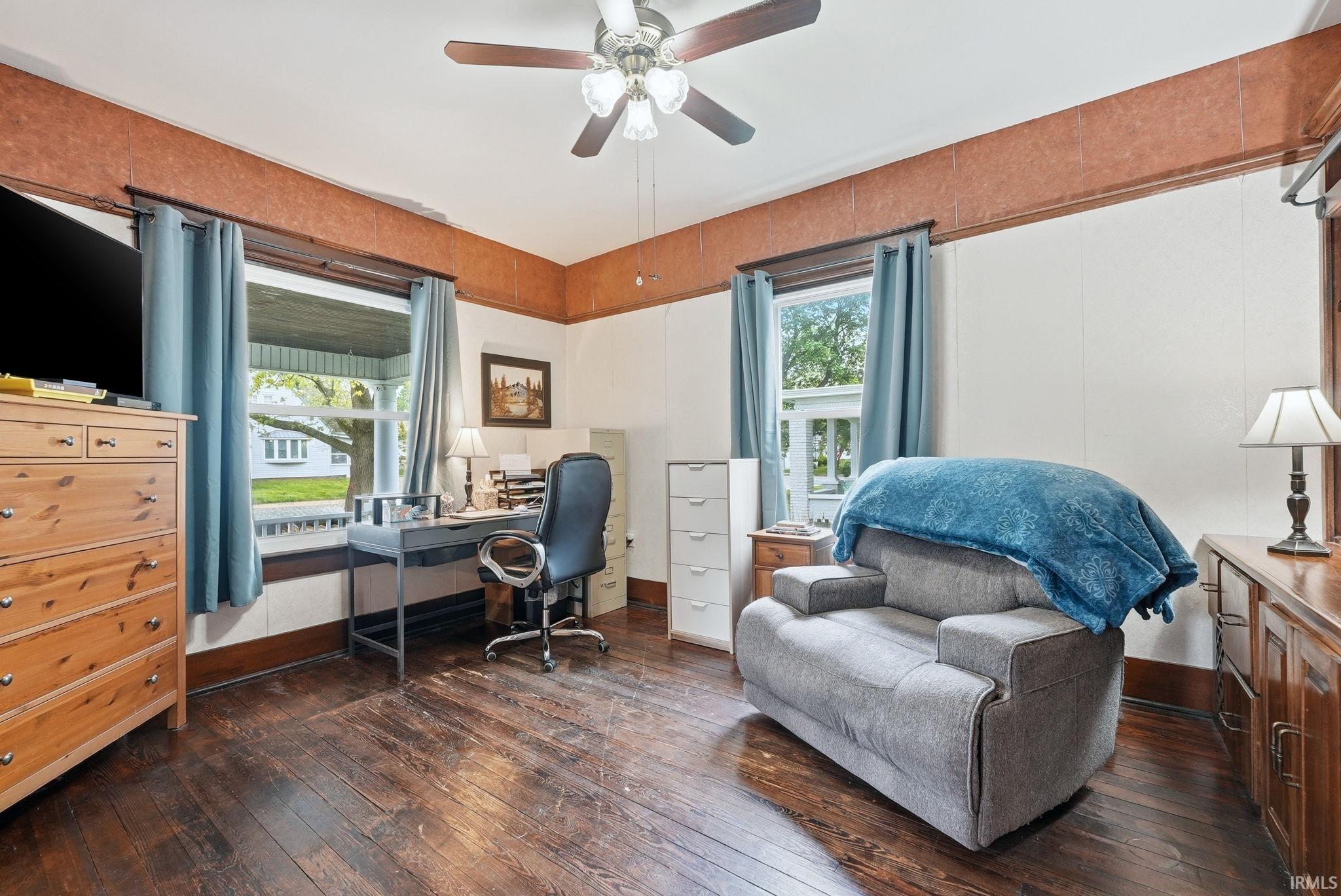Wood-finish flooring throughout, complemented by white paneled walls and a ceiling fan with integrated lighting