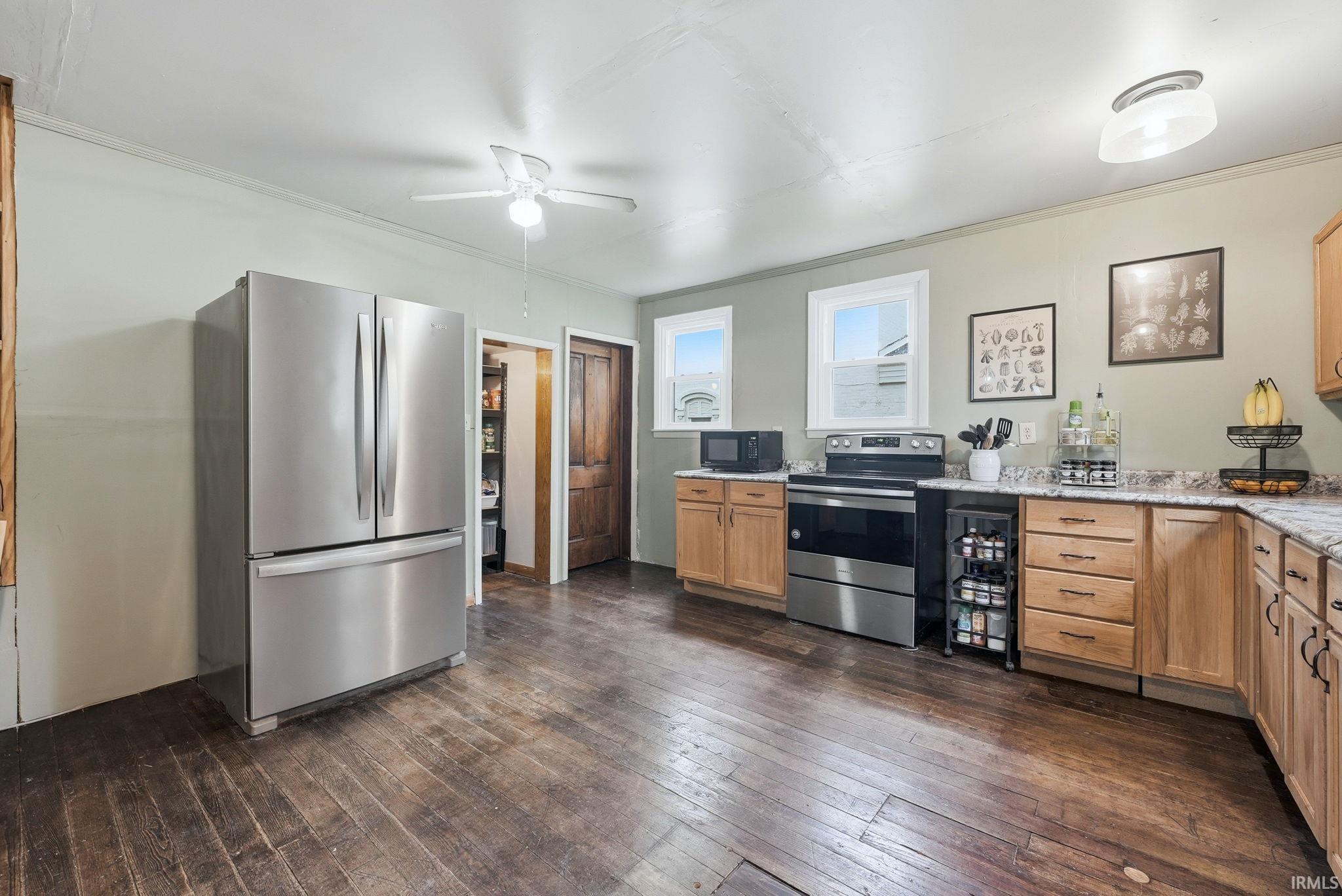 Kitchen featuring wood-finish flooring, light wood cabinetry, and light-toned countertops