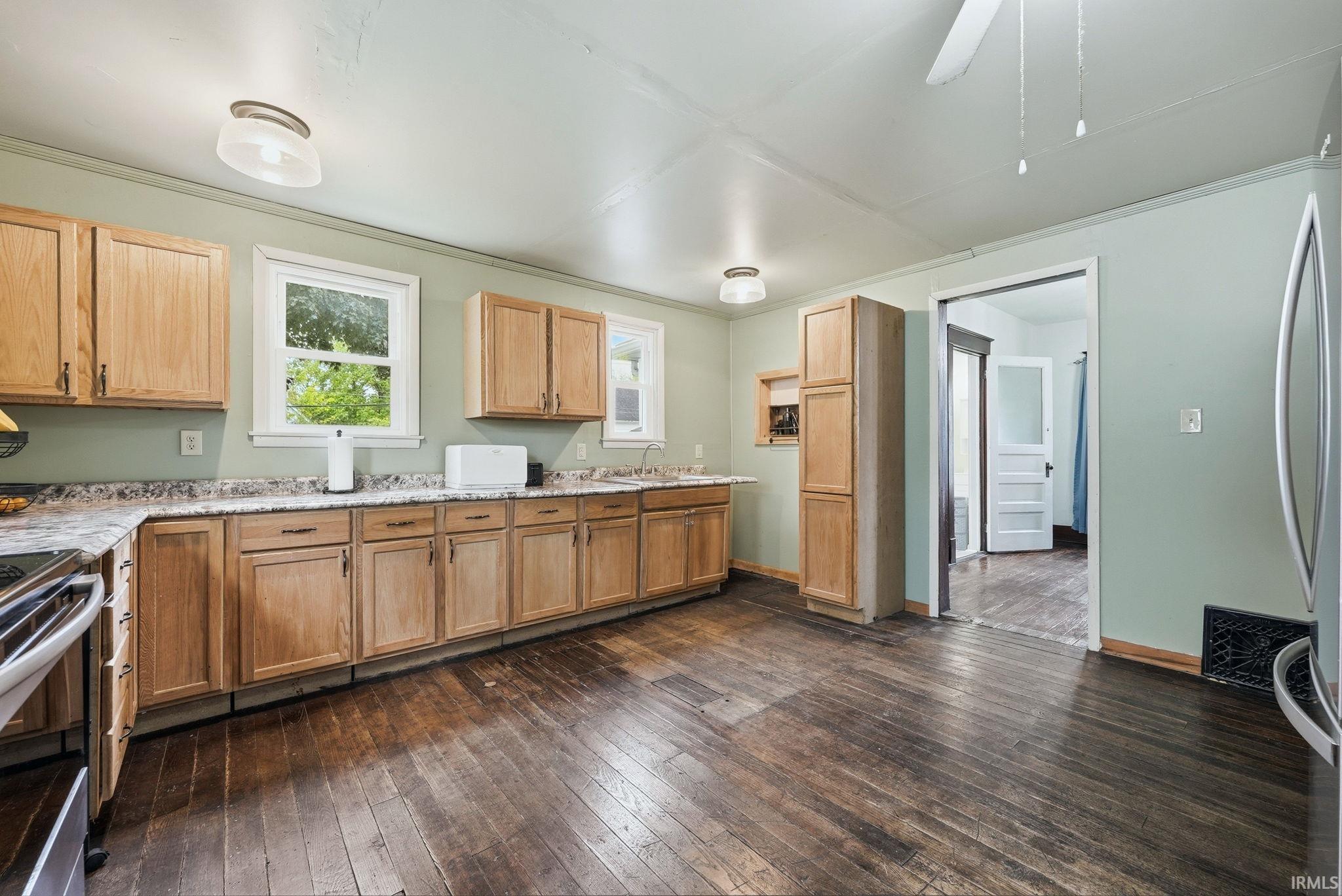 Kitchen featuring wood-finish flooring, light wood cabinetry, and speckled countertops