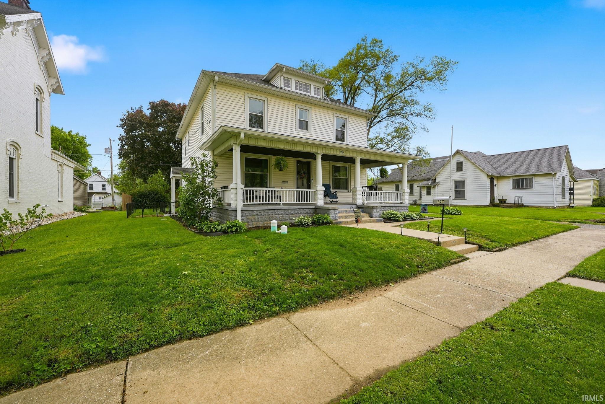 Two-story traditional residence featuring a full-width covered porch with white columns and railing