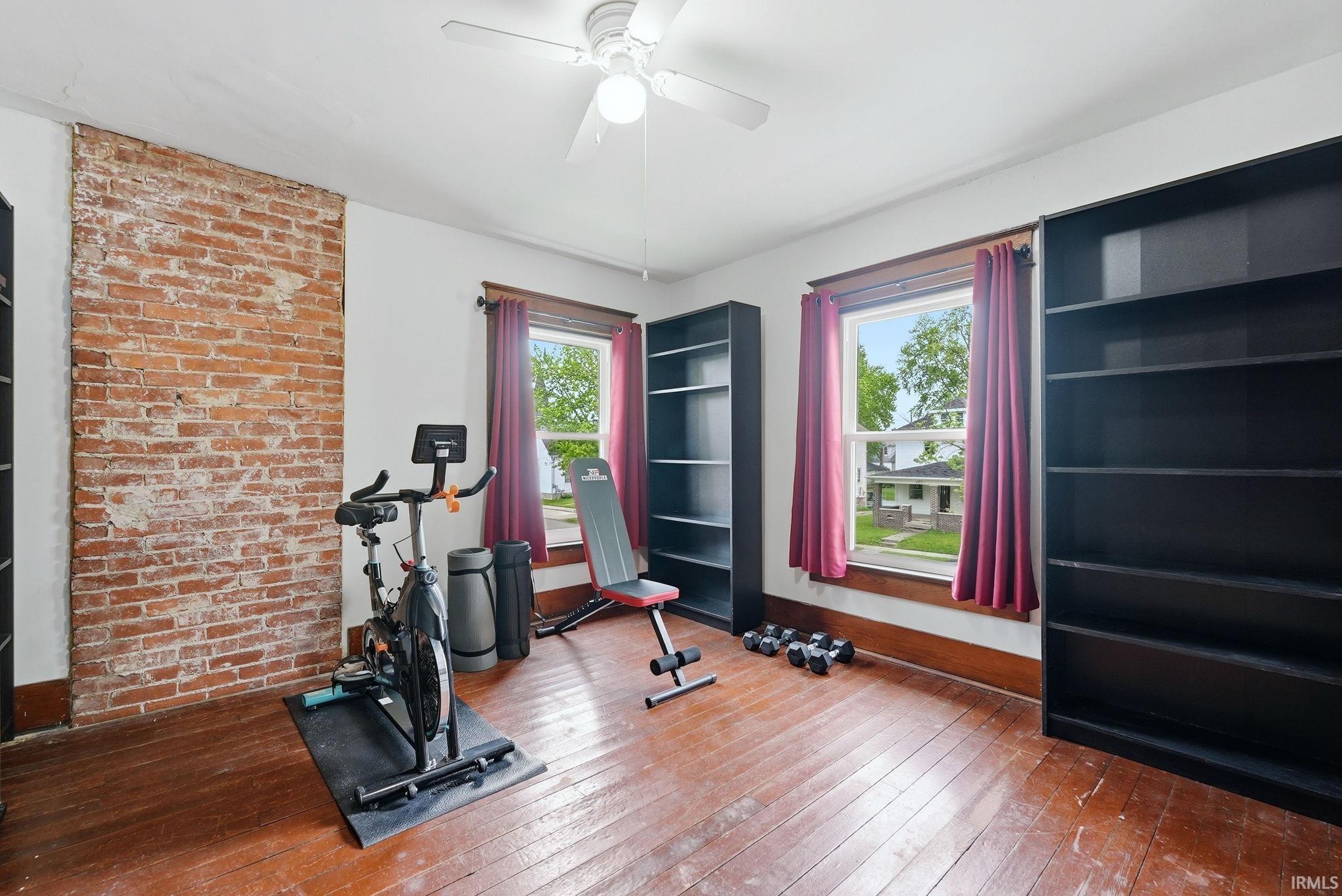 Exposed brick accent wall and hardwood flooring characterize this versatile room