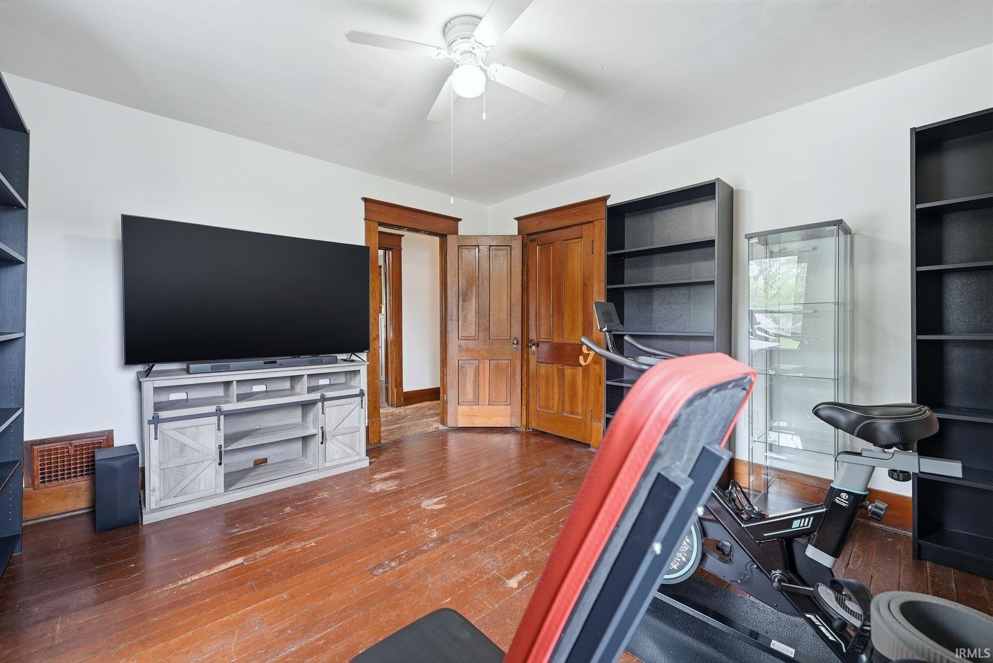Spacious room with wood-finish flooring and white walls