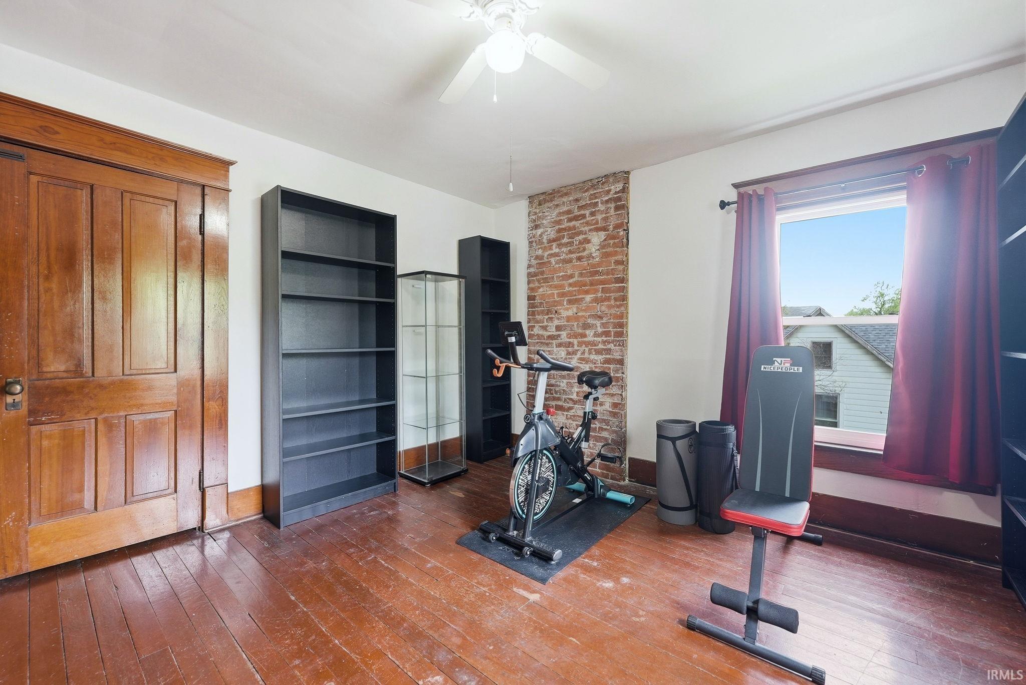 Hardwood flooring throughout featuring a visible brick accent wall