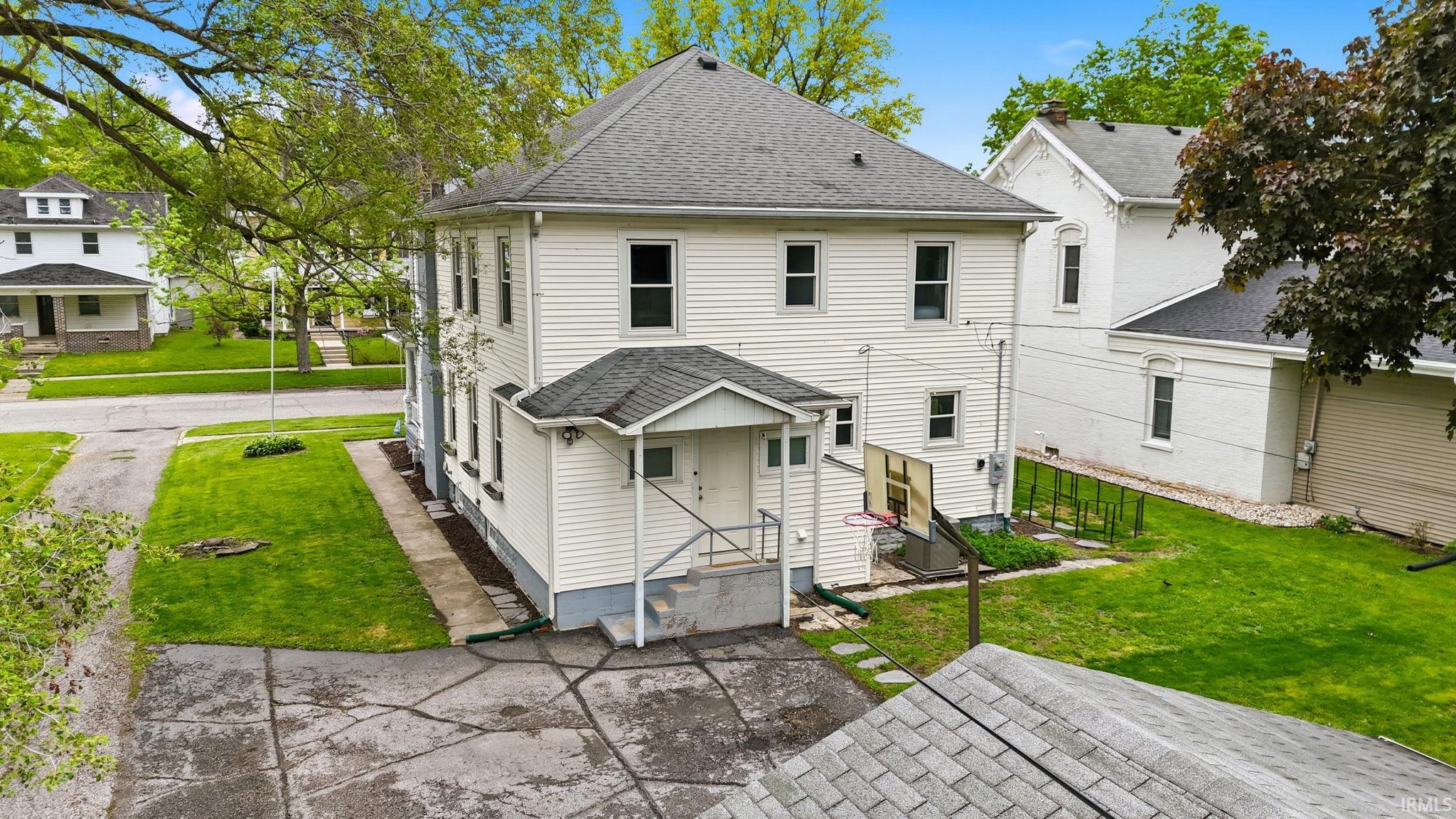 Two-story residence featuring white siding, a covered entry porch with railing, and a dark shingle roof