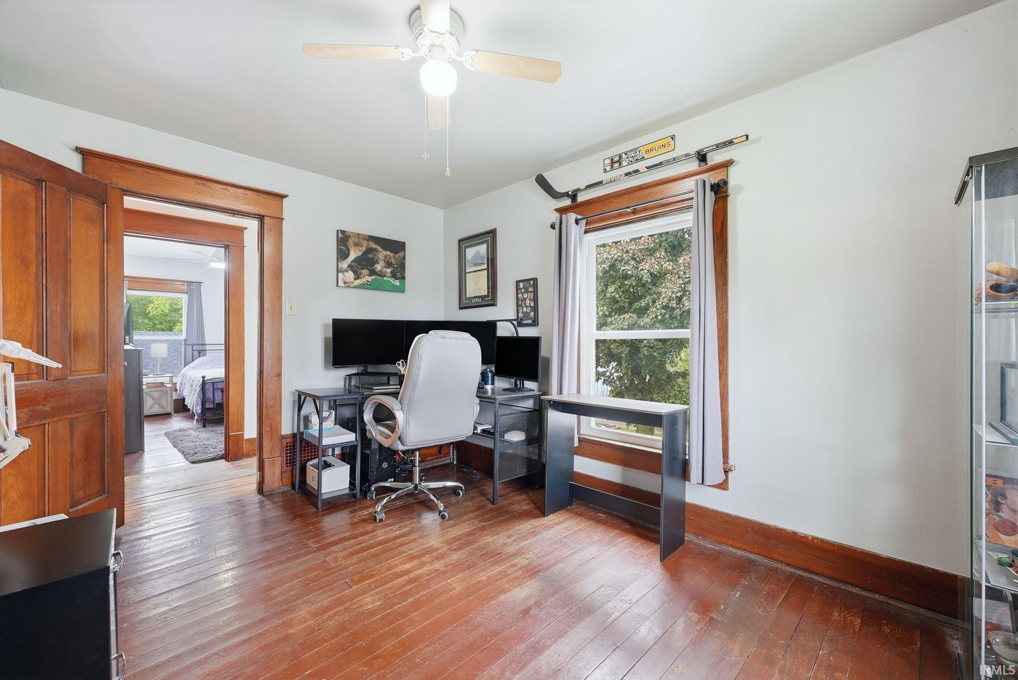 Hardwood flooring throughout, framed by natural wood trim and a single window