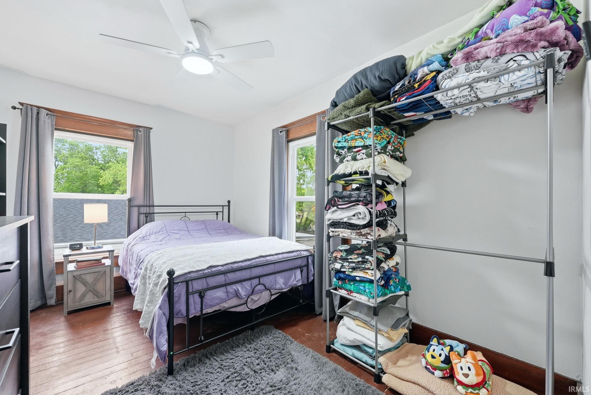Bedroom featuring wood-finish flooring, white walls, and a ceiling fan with integrated lighting