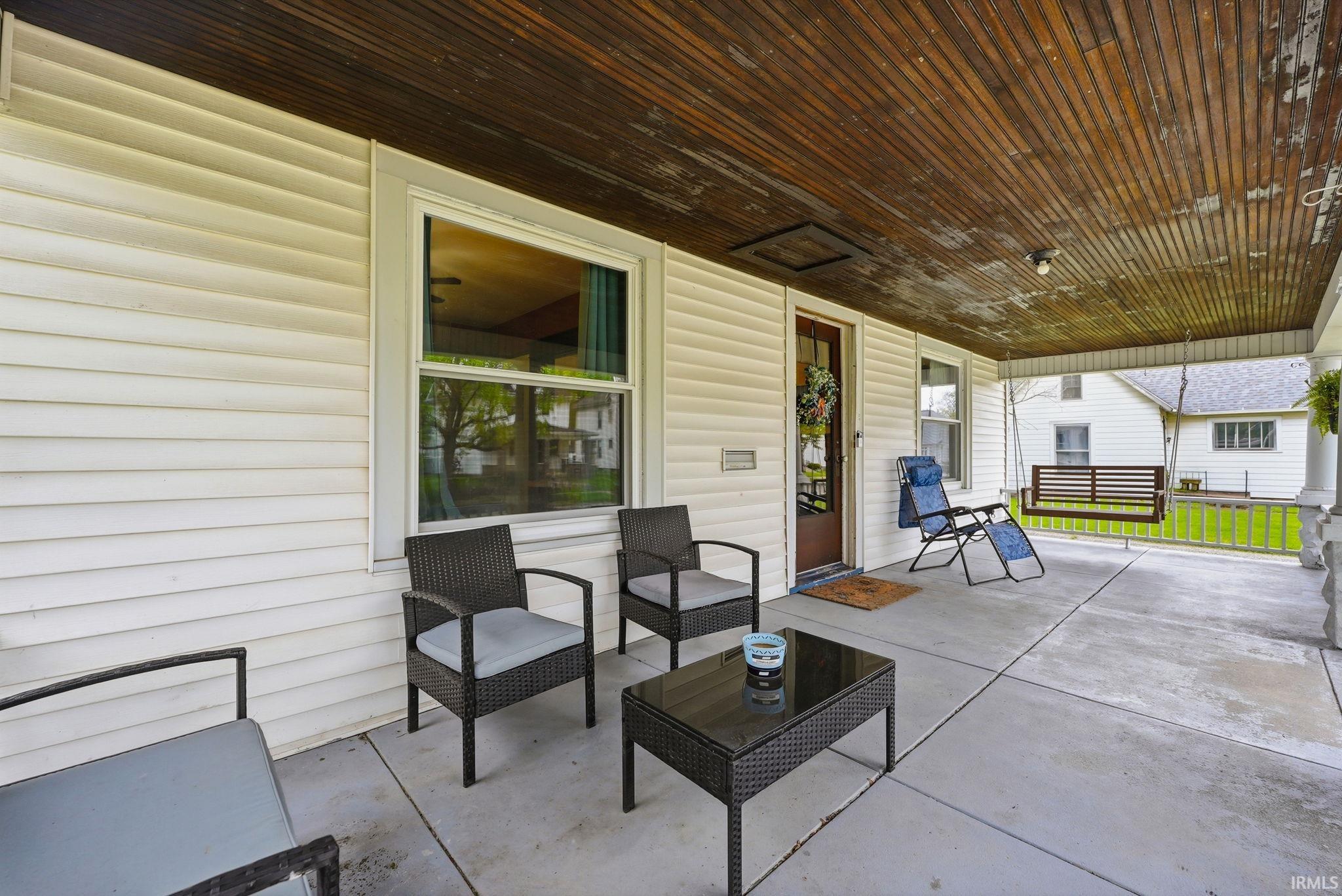 Front porch featuring a wood-finish plank ceiling, concrete flooring, and white vinyl siding